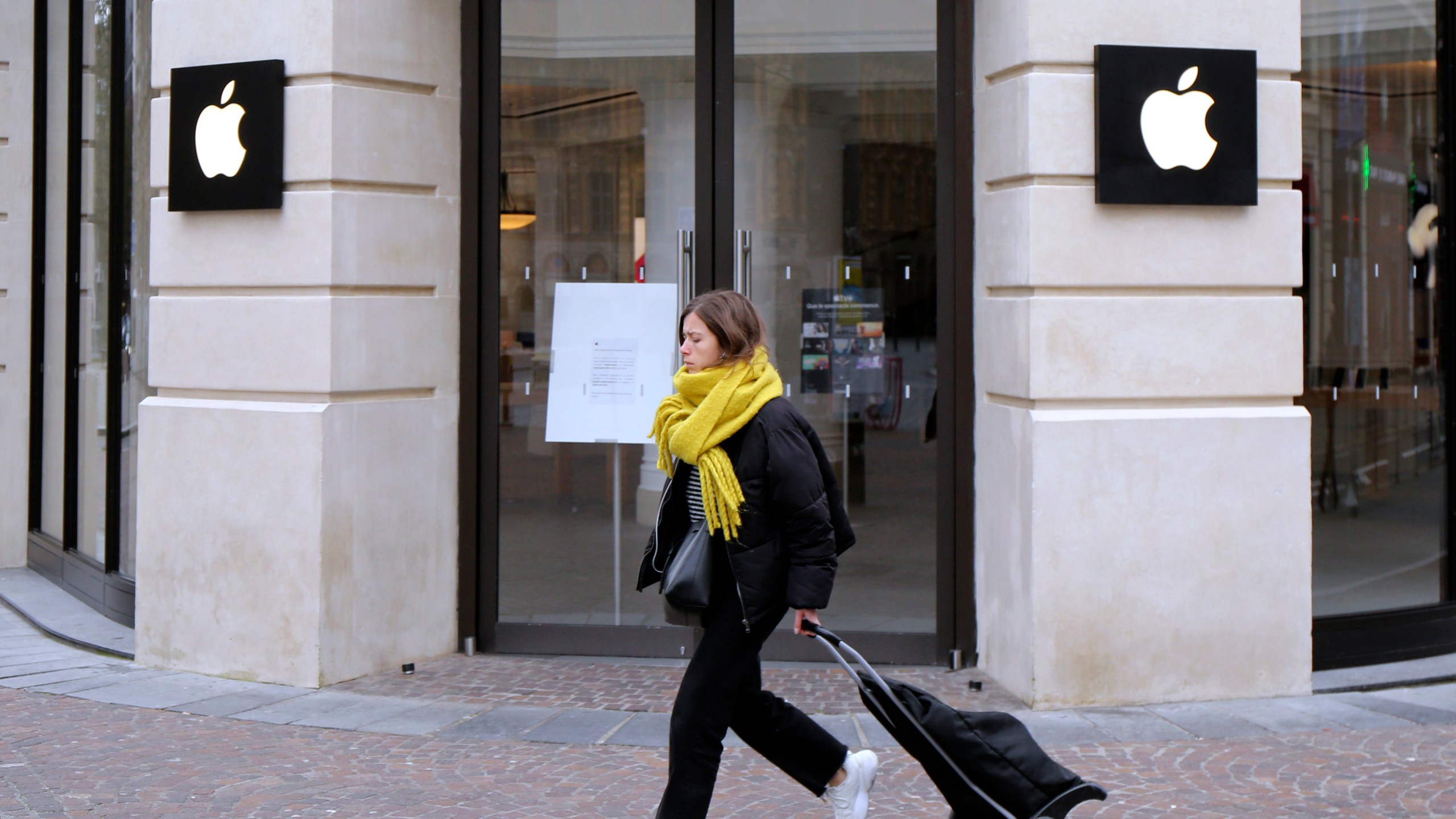 FILE - A woman walks past a closed Apple Store in Lille, northern France, Monday, March 16, 2020. A French watchdog ordered Apple to withdraw the iPhone 12 from the market because it is emitting too high levels of electromagnetic radiation. The National Frequencies Agency (ANFR), the body monitoring public exposure to radiations, called on Apple to "implement all available means to rapidly fix this malfunction," in a statement released on Tuesday Sept.12, 2023. (AP Photo/Michel Spingler, File)
