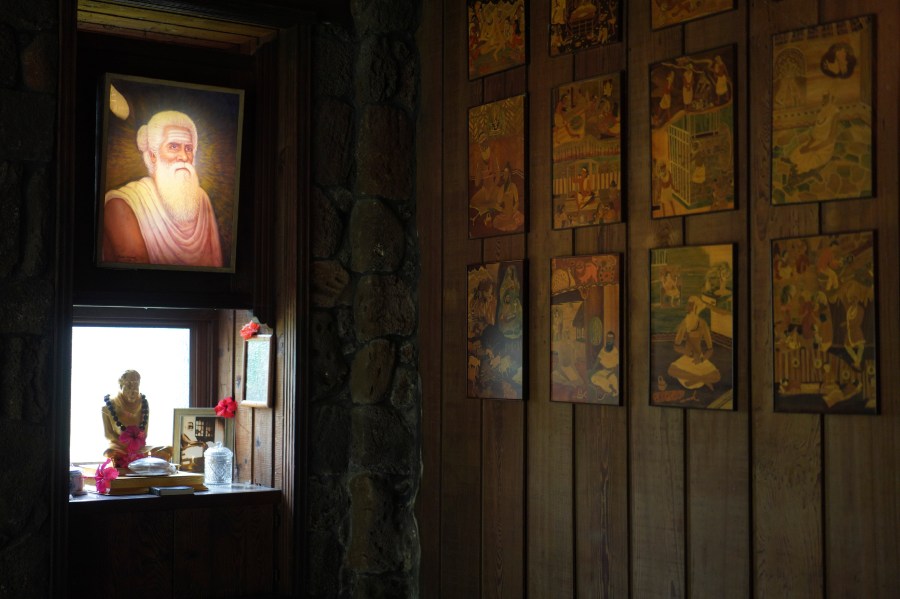 A lit photo of Satguru Sivaya Subramuniyaswami, left, the founding guru of Kauai's Hindu Monastery, hangs in a meditation room on July 13, 2023, in Kapaa, Hawaii. The temple monastery was founded in 1970. (AP Photo/Jessie Wardarski)