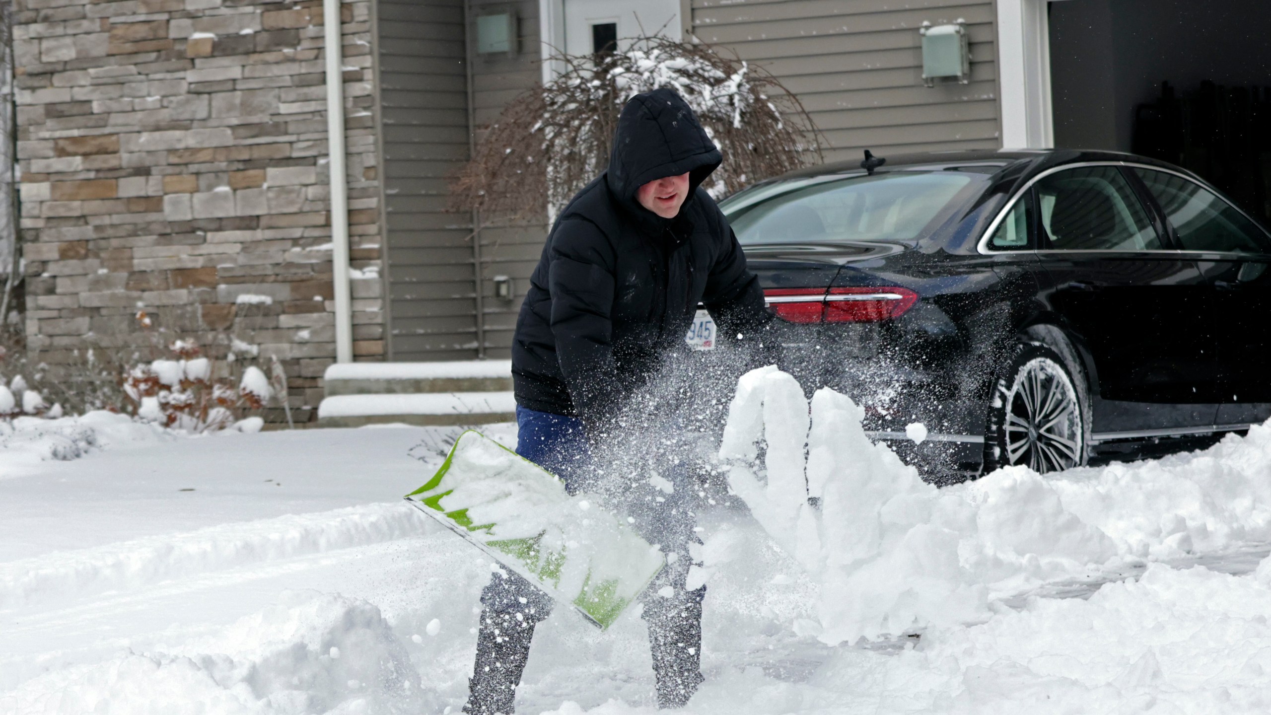 A man clears his driveway in Beachwood, Ohio, after heavy lake-effect snowfall arrived overnight, Tuesday, Nov. 28, 2023. A winter storm shut down schools in Cleveland and other areas Tuesday and the blanket of snow made driving on heavily traveled Interstate 90 in northern Ohio treacherous. (David Petkiewicz/Cleveland.com via AP)