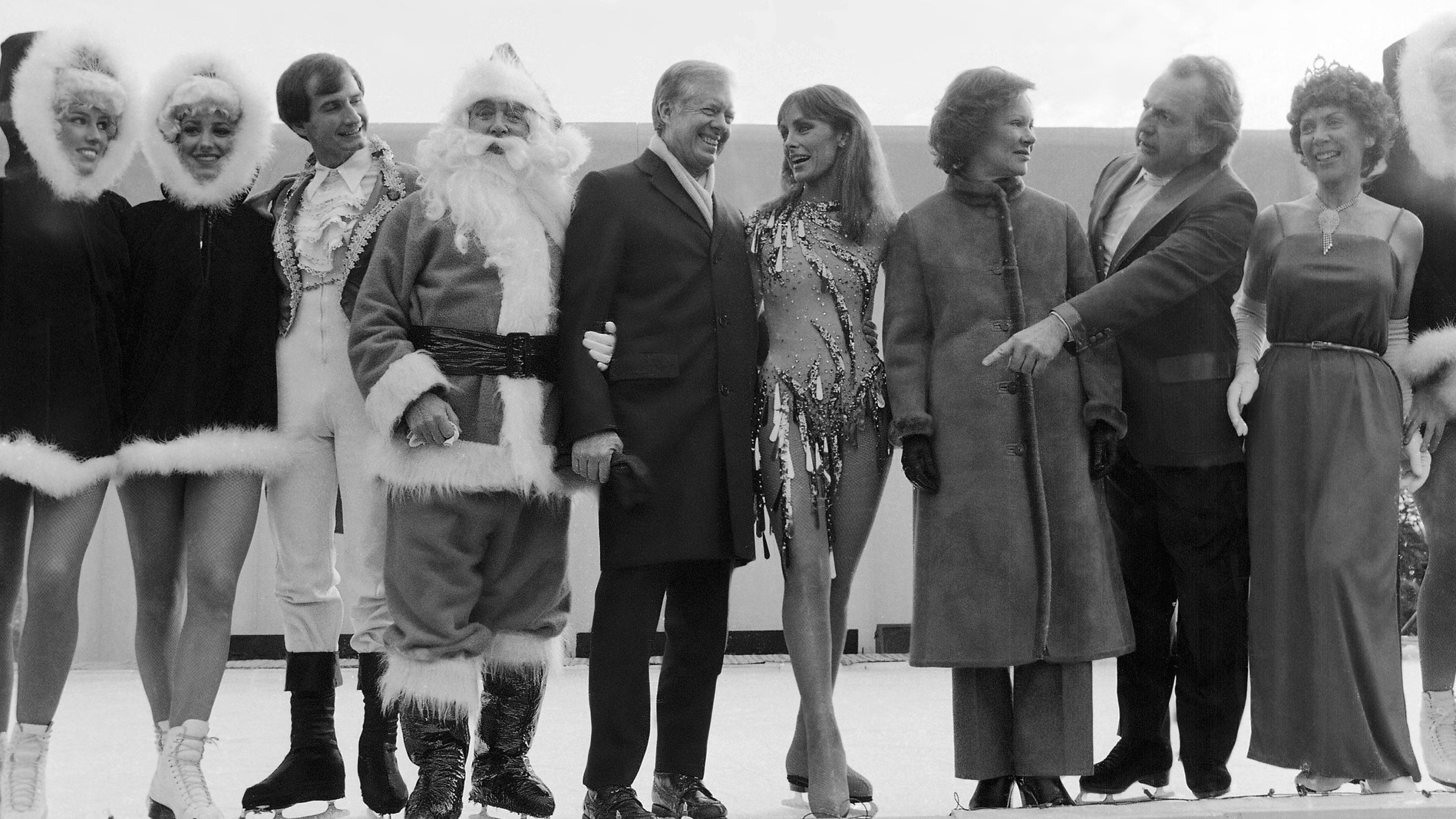 FILE - President Jimmy Carter calls for other performers to join himself, Santa Claus and ice skating star Peggy Fleming for pictures at a White House reception for U.S. Secret Service agents and military aides in Washington, Dec. 22, 1980. Jill Biden is bringing a holiday ice rink to the White House lawn for children to skate and play hockey during the holidays. The first lady was set to announce the rink after sunset on Wednesday. She was to be joined by 1988 Olympic figure skater Brian Boitano and the Snoopy character, among others. The White House says the rink will operate during December. (AP Photo/Dennis Cook, File)