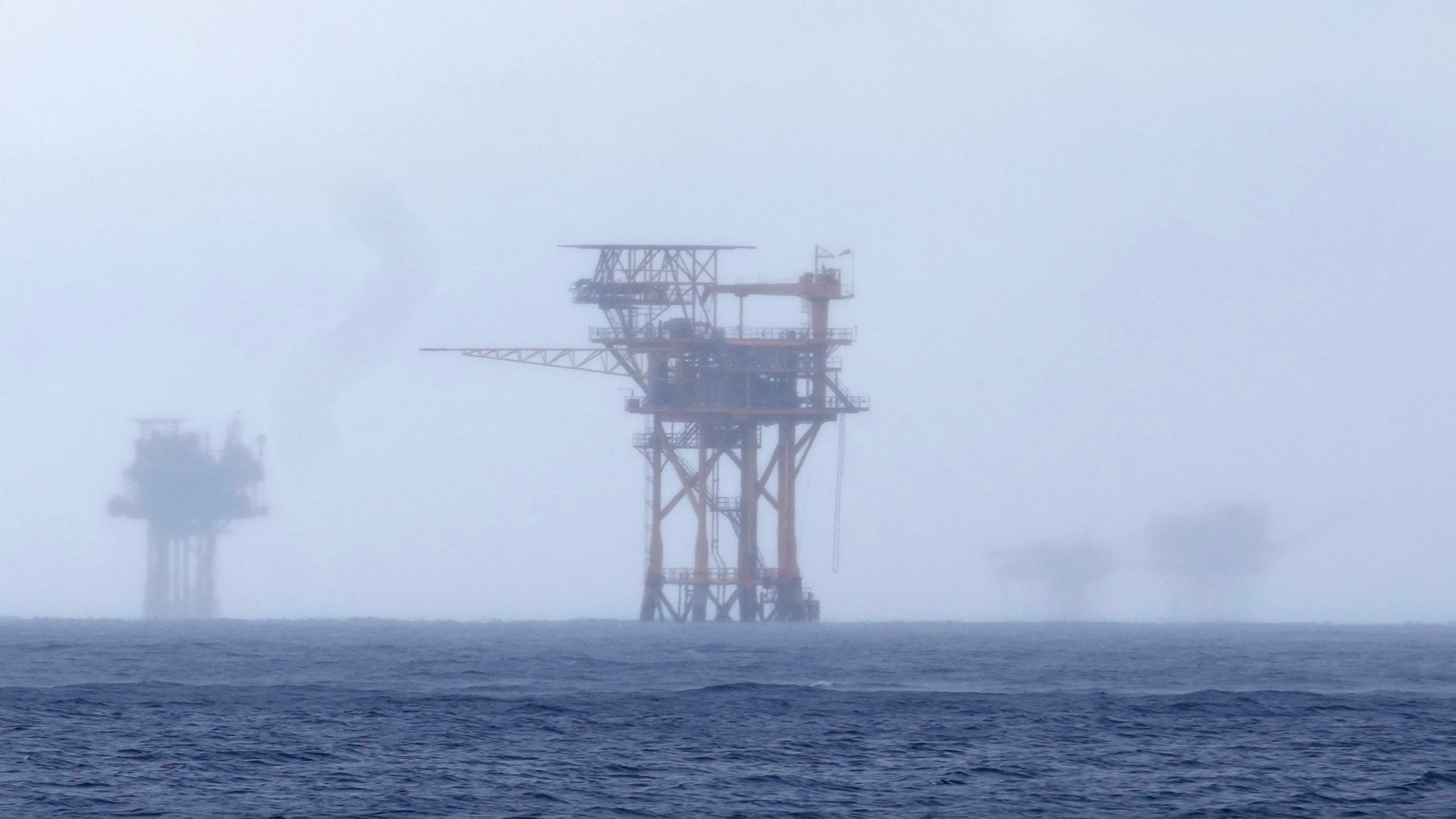 CORRECTS TO 382 MILLION NOT 328 FILE - Oil platforms are visible through the haze near the Flower Garden Banks National Marine Sanctuary in the Gulf of Mexico, off the coast of Galveston, Texas, Sept. 16, 2023. Oil companies offered $382 million for drilling leases in the Gulf Wednesday after courts rejected the Biden administration's plans to scale back the sale to protect an endangered whale species. (AP Photo/LM Otero, file)