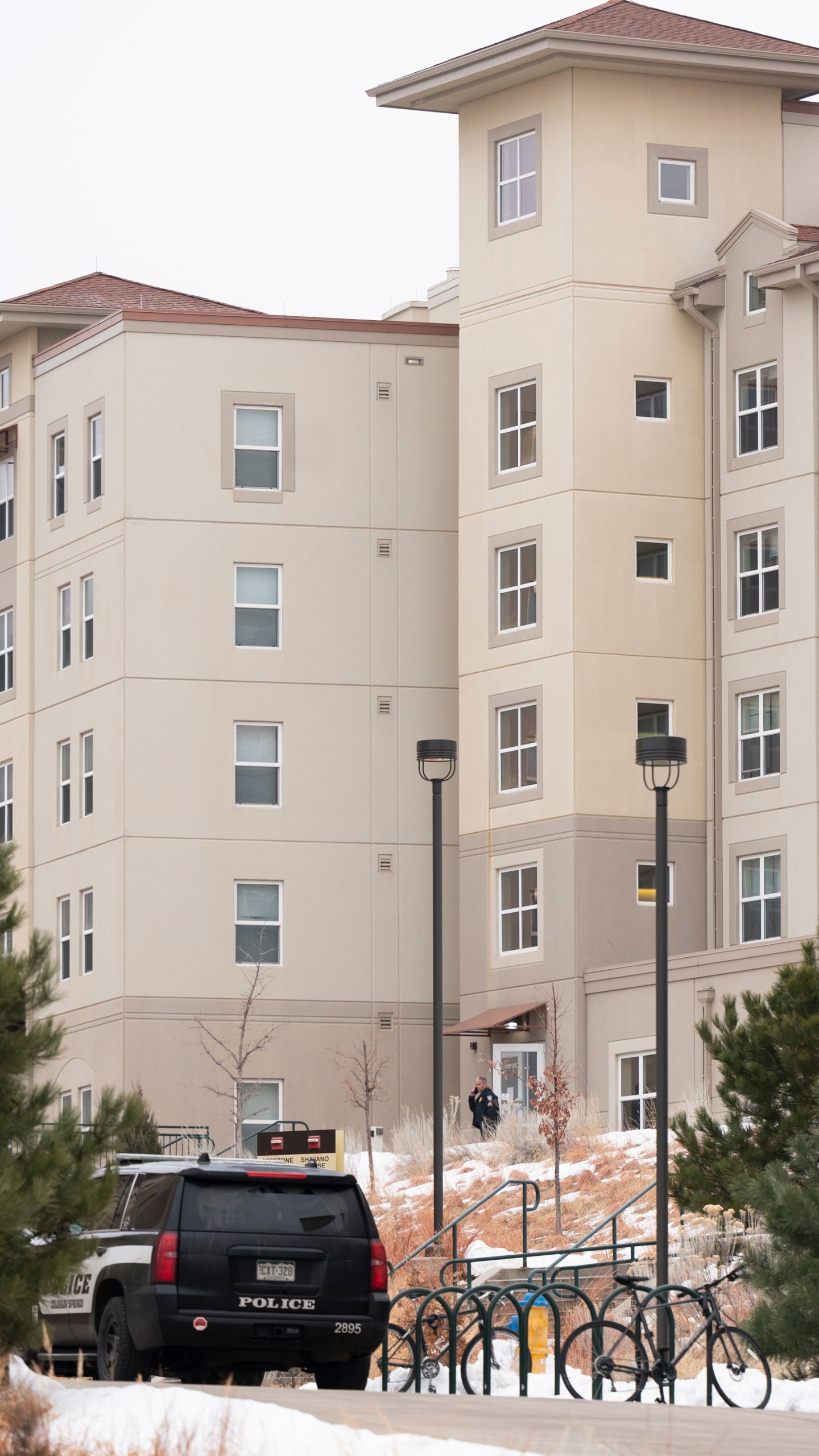 A police officer stands outside a dorm in the Village at Alpine Valley housing, Friday, Feb. 16, 2024, as police investigate a shooting on the University of Colorado Colorado Springs campus in Colorado Springs, Colo. (Christian Murdock/The Gazette via AP)