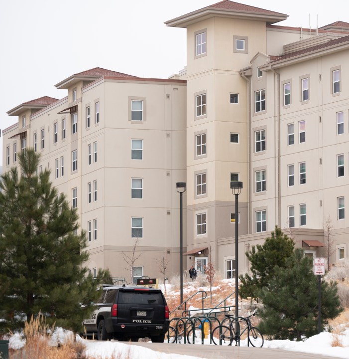 A police officer stands outside a dorm in the Village at Alpine Valley housing, Friday, Feb. 16, 2024, as police investigate a shooting on the University of Colorado Colorado Springs campus in Colorado Springs, Colo. (Christian Murdock/The Gazette via AP)