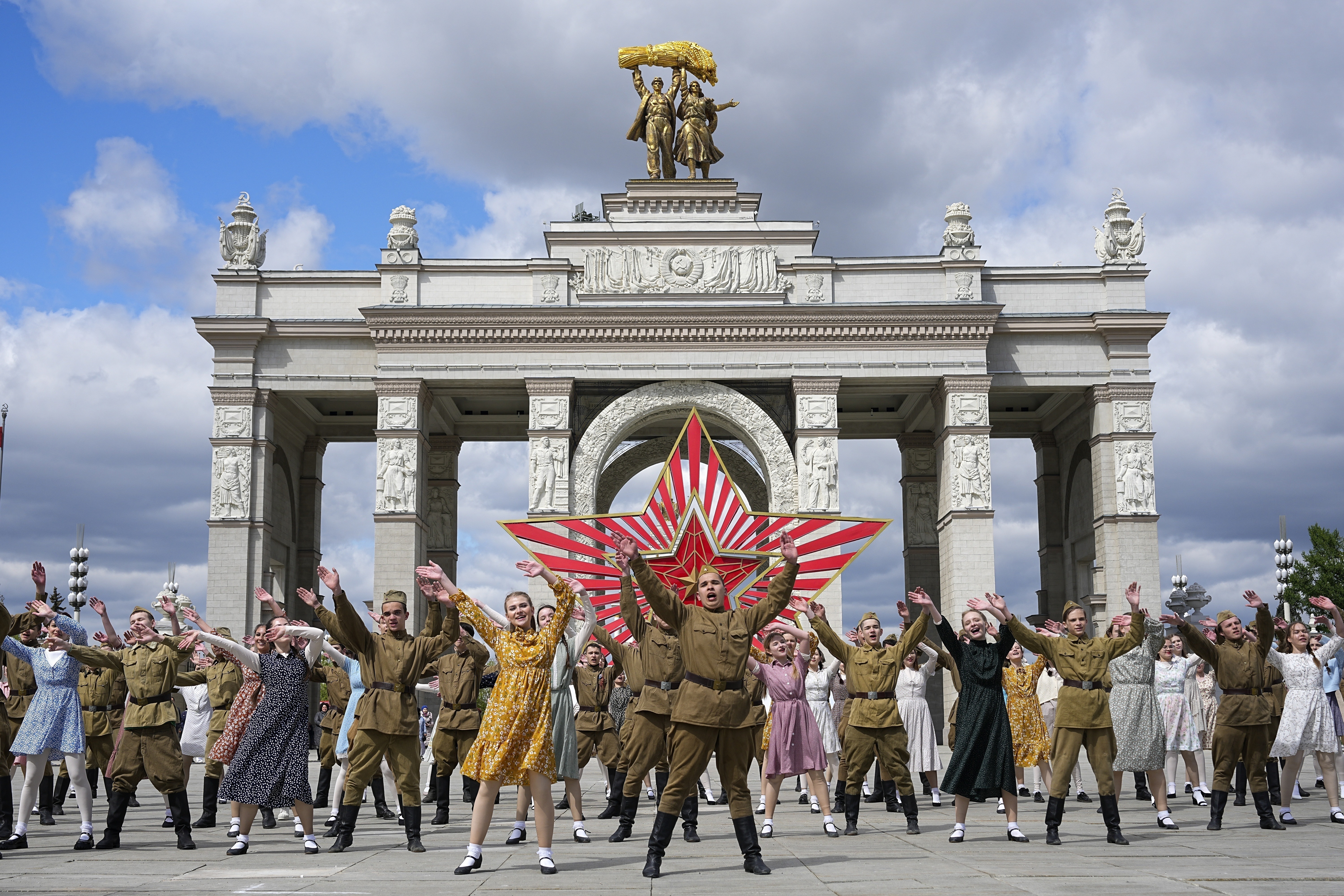 FILE - Moscow students dressed in the fashion of the middle of the last century and Soviet style uniform perform "Victory Waltz" as a part of Victory Day celebration in front of the historical main gates of VDNKh, The Exhibition of Achievements of National Economy, with the red star in the background in Moscow, Russia, Saturday, May 6, 2023. In Russia, history has long become a propaganda tool used to advance the Kremlin's political goals. In an effort to rally people around the flag, the authorities have sought to magnify the country's past victories while glossing over the more sordid chapters of its history. (AP Photo, File)