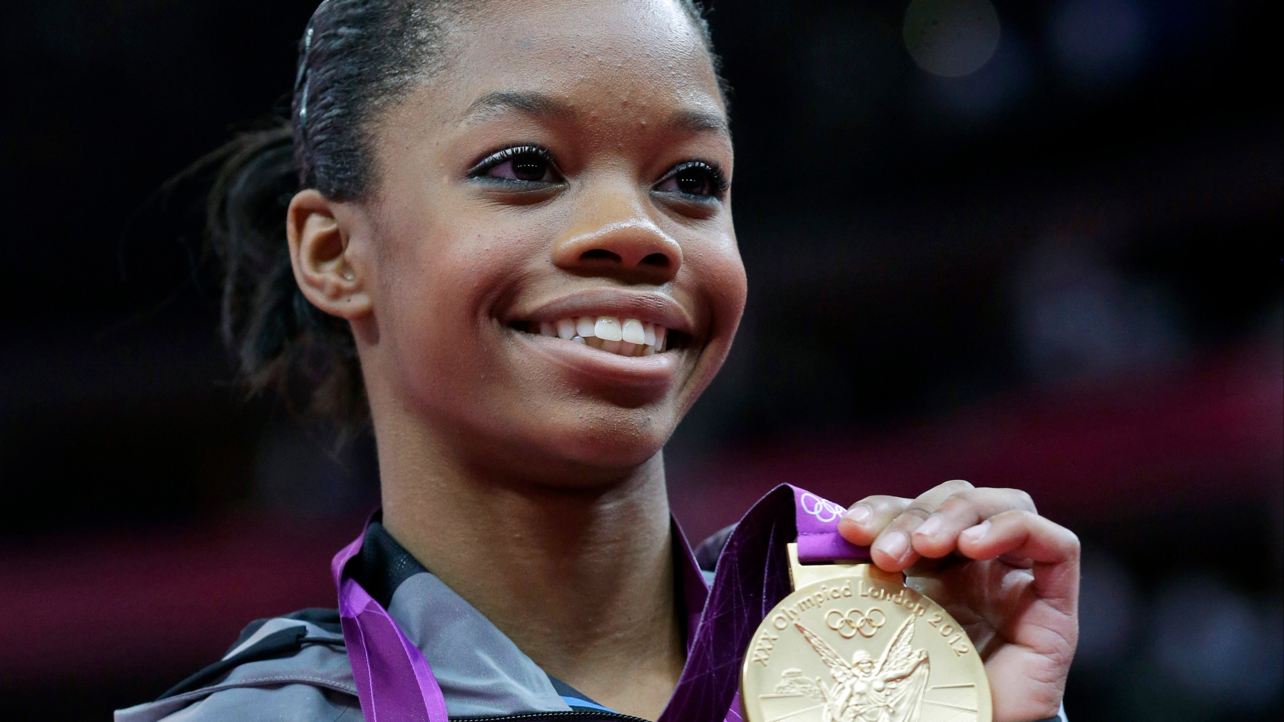 FILE - U.S. gymnast Gabby Douglas displays her gold medal during the artistic gymnastics women's individual all-around competition at the 2012 Summer Olympics in London, Aug. 2, 2012. Douglas pulled out of this weekend's 2024 Winter Cup in Louisville after testing positive for COVID-19. The meet was to be Douglas' first competition since the 2016 Olympics (AP Photo/Julie Jacobson, File)