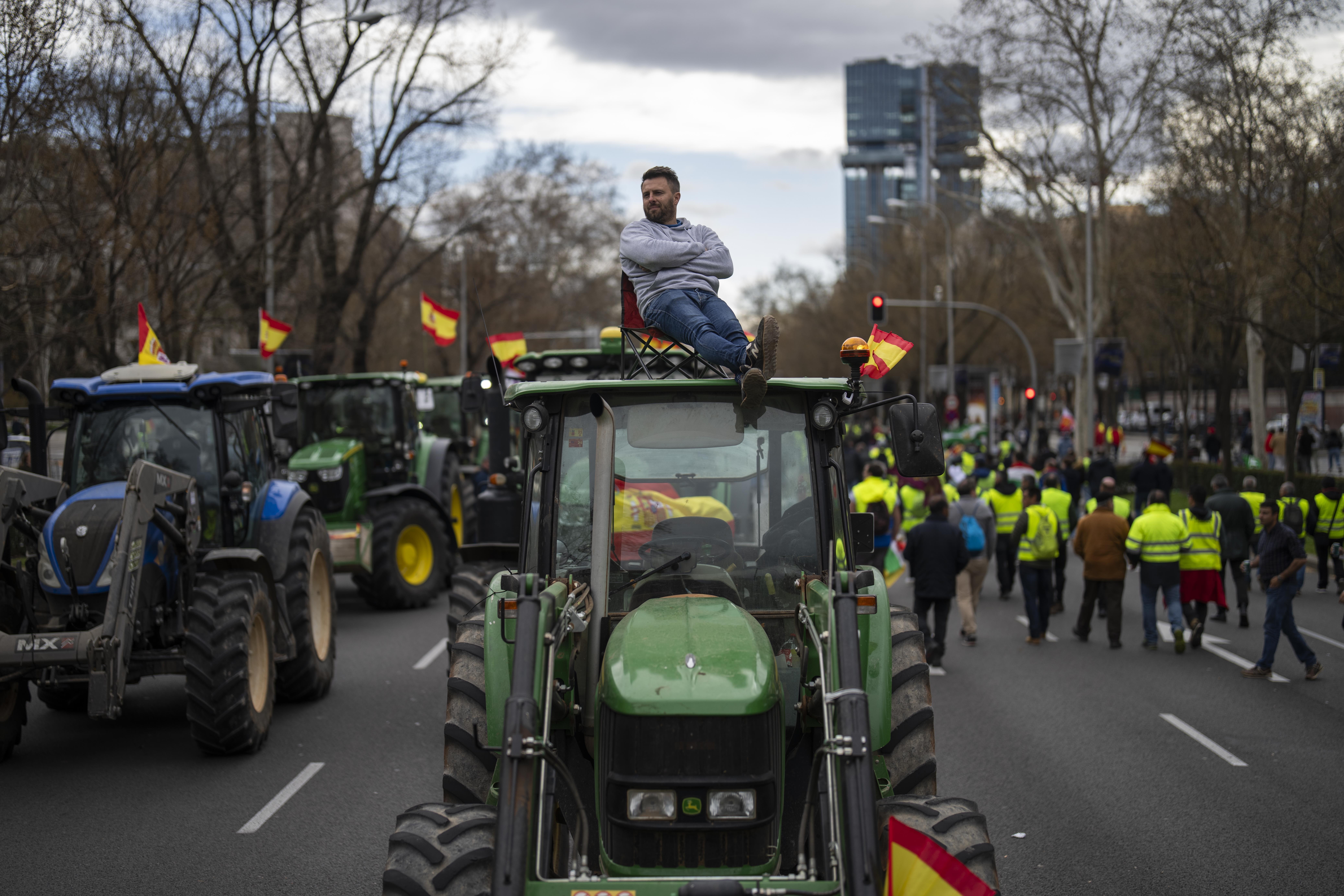 A farmer sits atop a tractor during a protest outside the European Parliament offices in Madrid, Spain, Monday, Feb. 26, 2024. (AP Photo/Bernat Armangue)