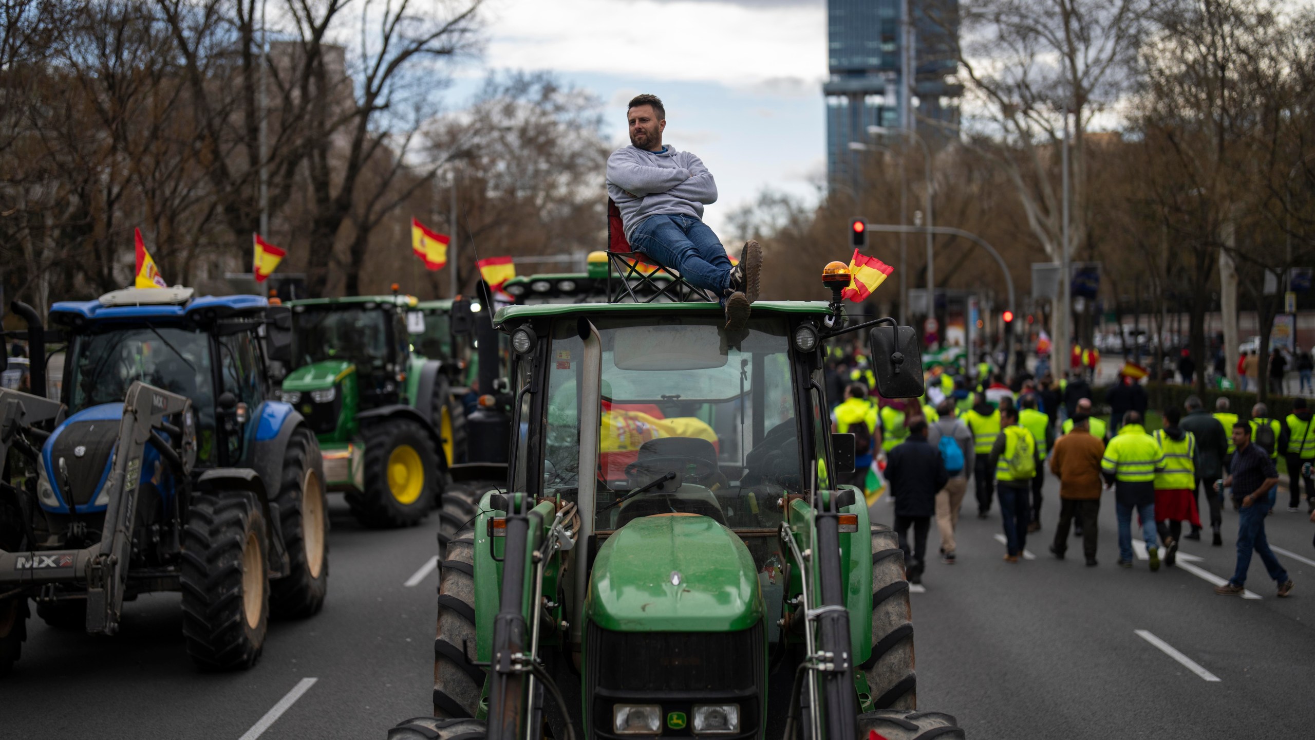 A farmer sits atop a tractor during a protest outside the European Parliament offices in Madrid, Spain, Monday, Feb. 26, 2024. (AP Photo/Bernat Armangue)