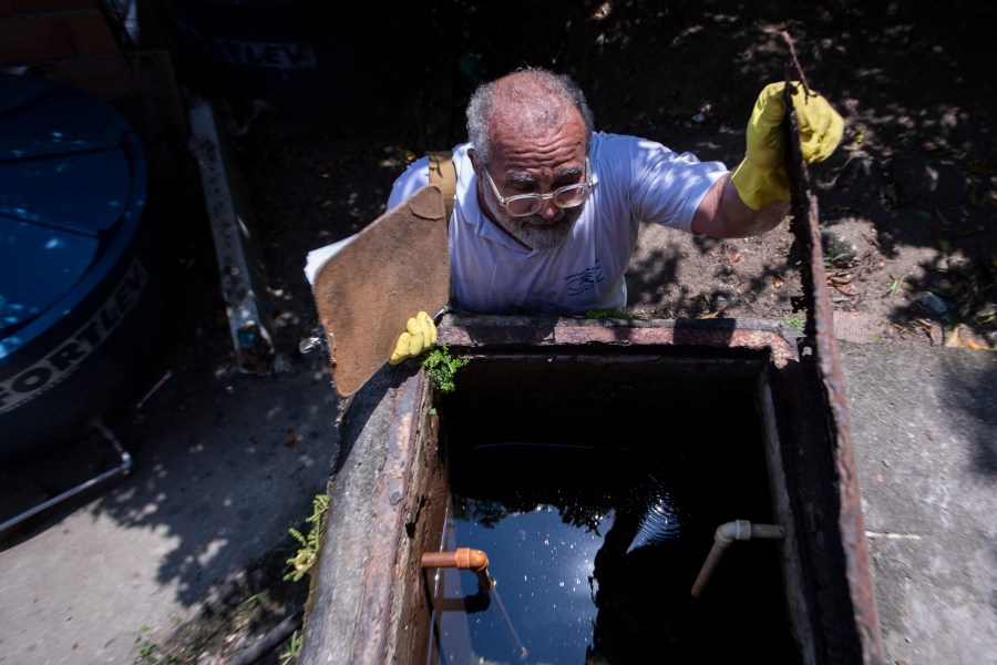 Augusto Cesar, a city worker who combats endemic diseases, inspects a water tank where mosquitoes can breed to eradicate the Aedes aegypti mosquito which can spread dengue in the Morro da Penha favela of Niteroi, Brazil, Friday, March 1, 2024. (AP Photo/Bruna Prado)