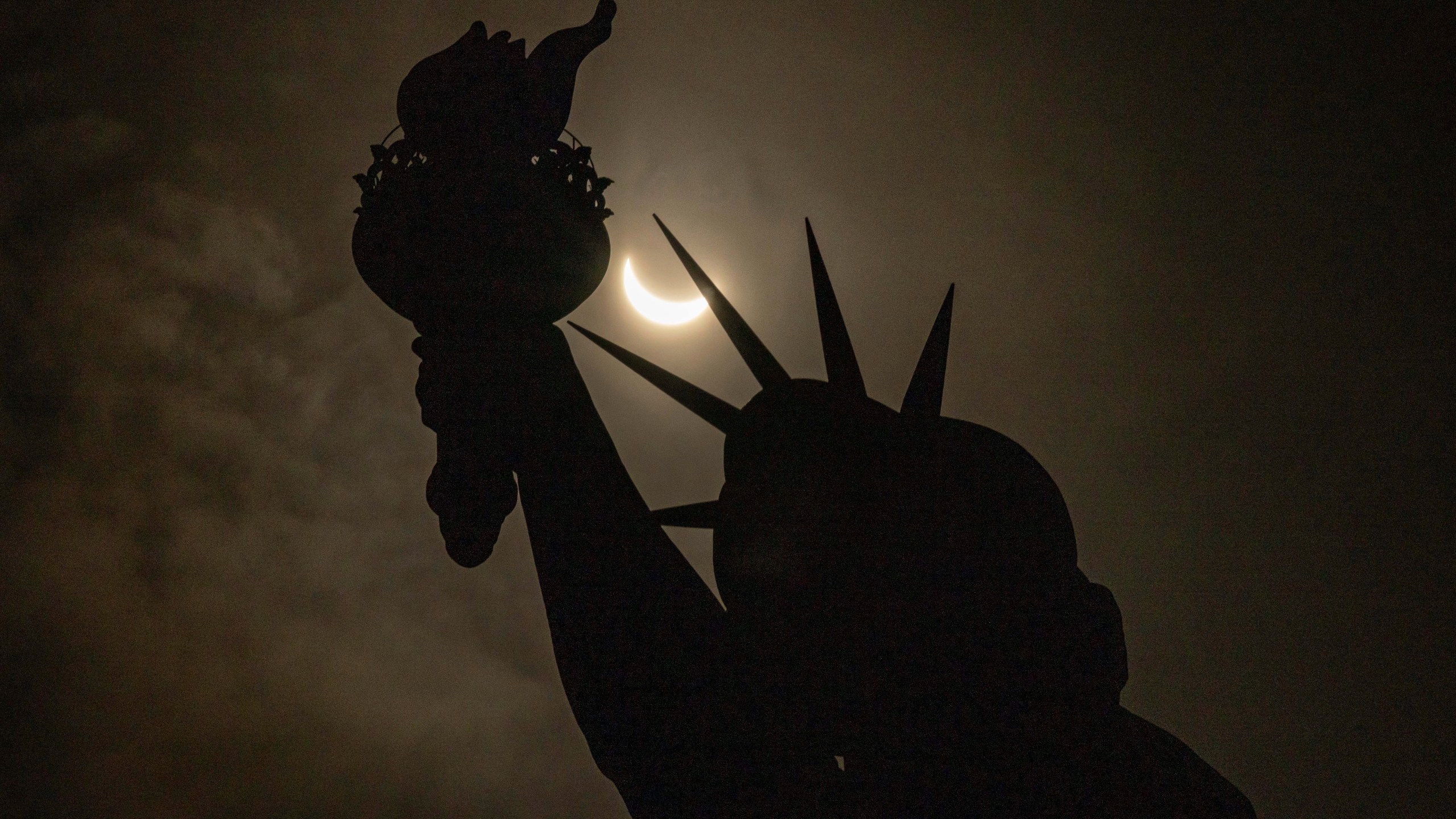 The moon partially covers the sun behind the Statue of Liberty during the a solar eclipse on the Liberty Island, Monday, April. 8, 2024, in New York. (AP Photo/Yuki Iwamura)