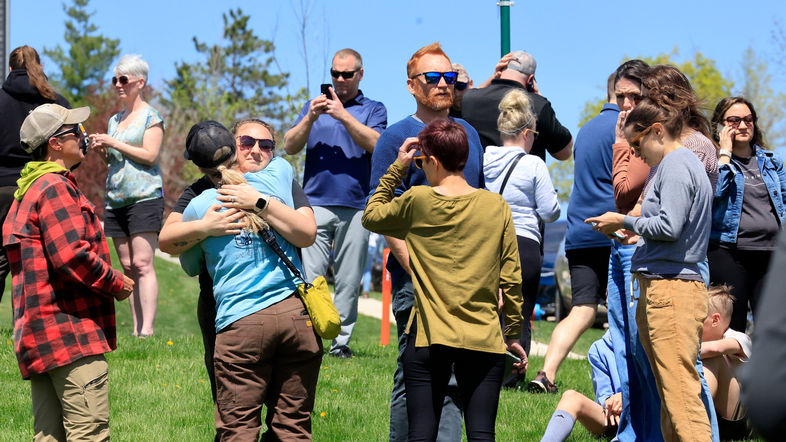 People gather at a site designated for parent and student reunifications following a report of a armed person outside Mount Horeb Middle School in Mount Horeb, Wis., Wednesday, May 1, 2024. (John Hart/Wisconsin State Journal via AP)