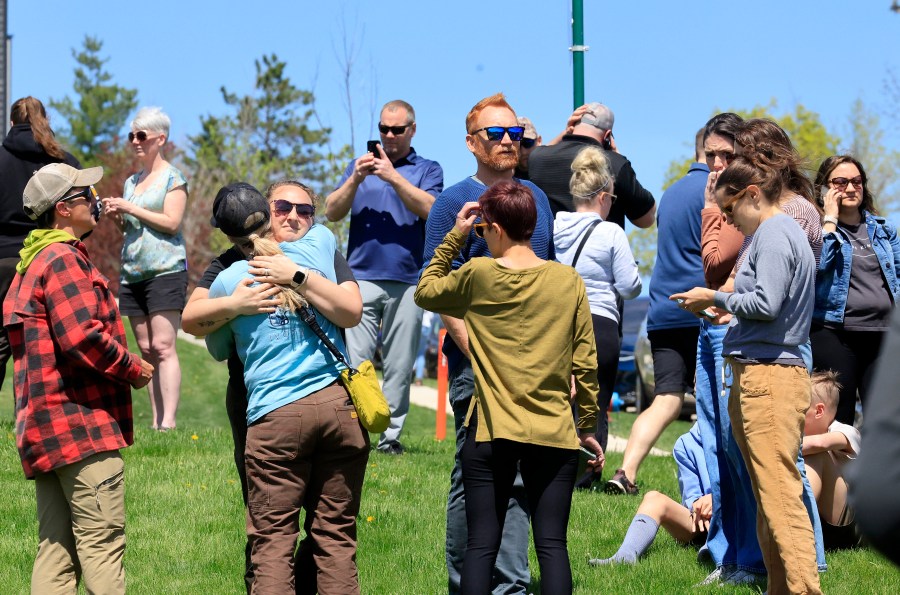 People gather at a site designated for parent and student reunifications following a report of a armed person outside Mount Horeb Middle School in Mount Horeb, Wis., Wednesday, May 1, 2024. (John Hart/Wisconsin State Journal via AP)