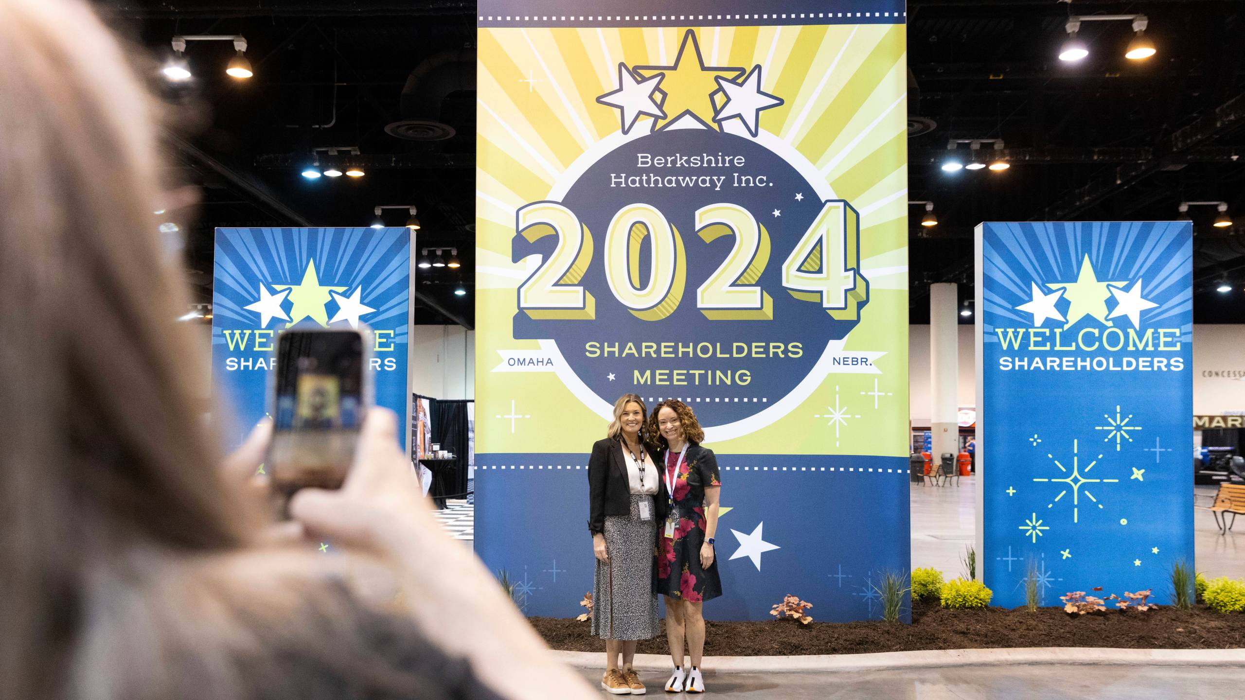 From left, D'Ann Rhoten takes a photo of Brittany Thornton and Melissa Shapiro in the exhibit hall of the Berkshire Hathaway annual meeting on Saturday, May 4, 2024, in Omaha, Neb. (AP Photo/Rebecca S. Gratz)