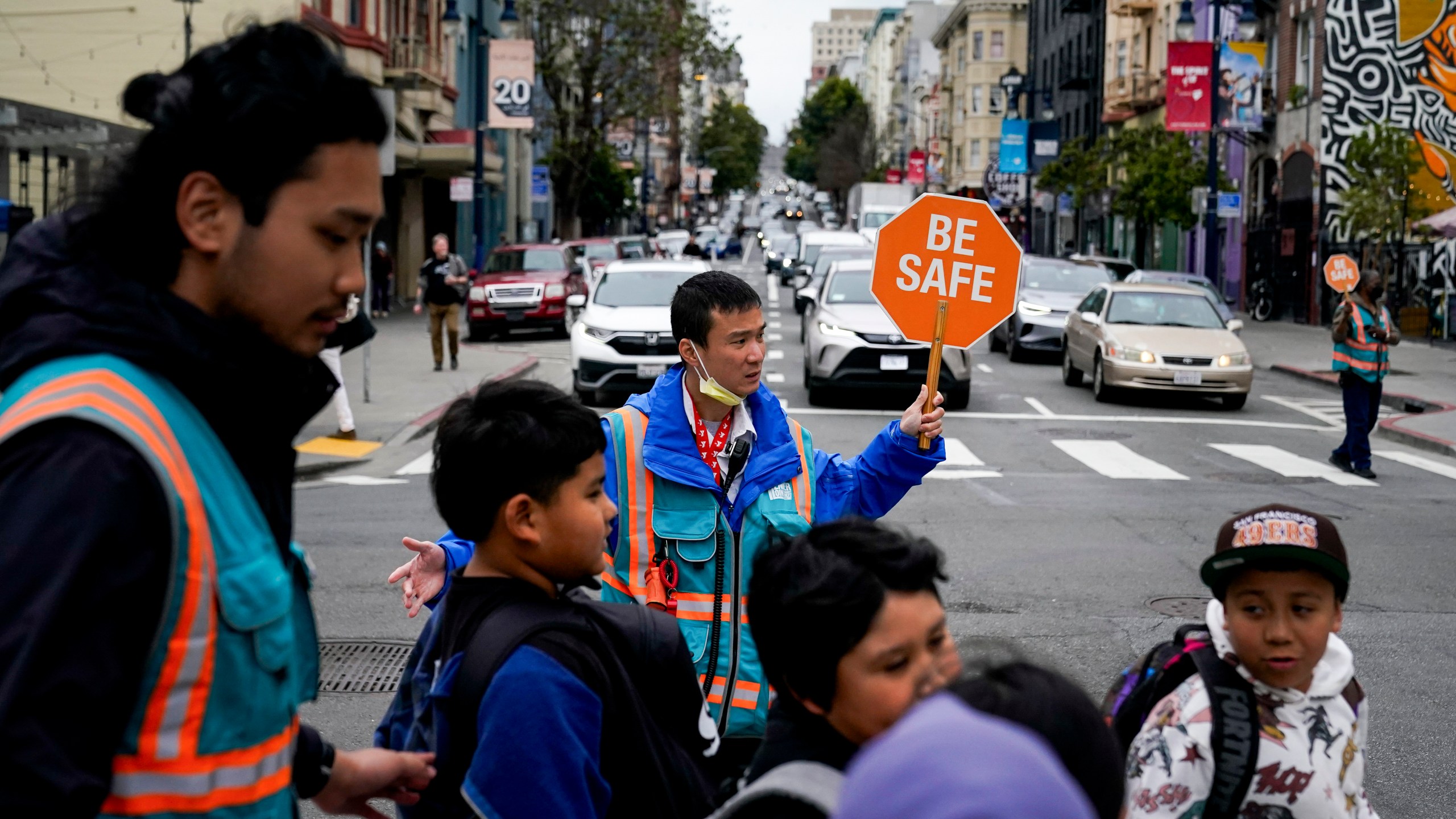 Hung Truong, background, with Safe Passage makes sure children make it safely to the Boys & Girls Clubs of San Francisco for after-school programs Wednesday, March 27, 2024, in San Francisco. (AP Photo/Godofredo A. Vásquez)