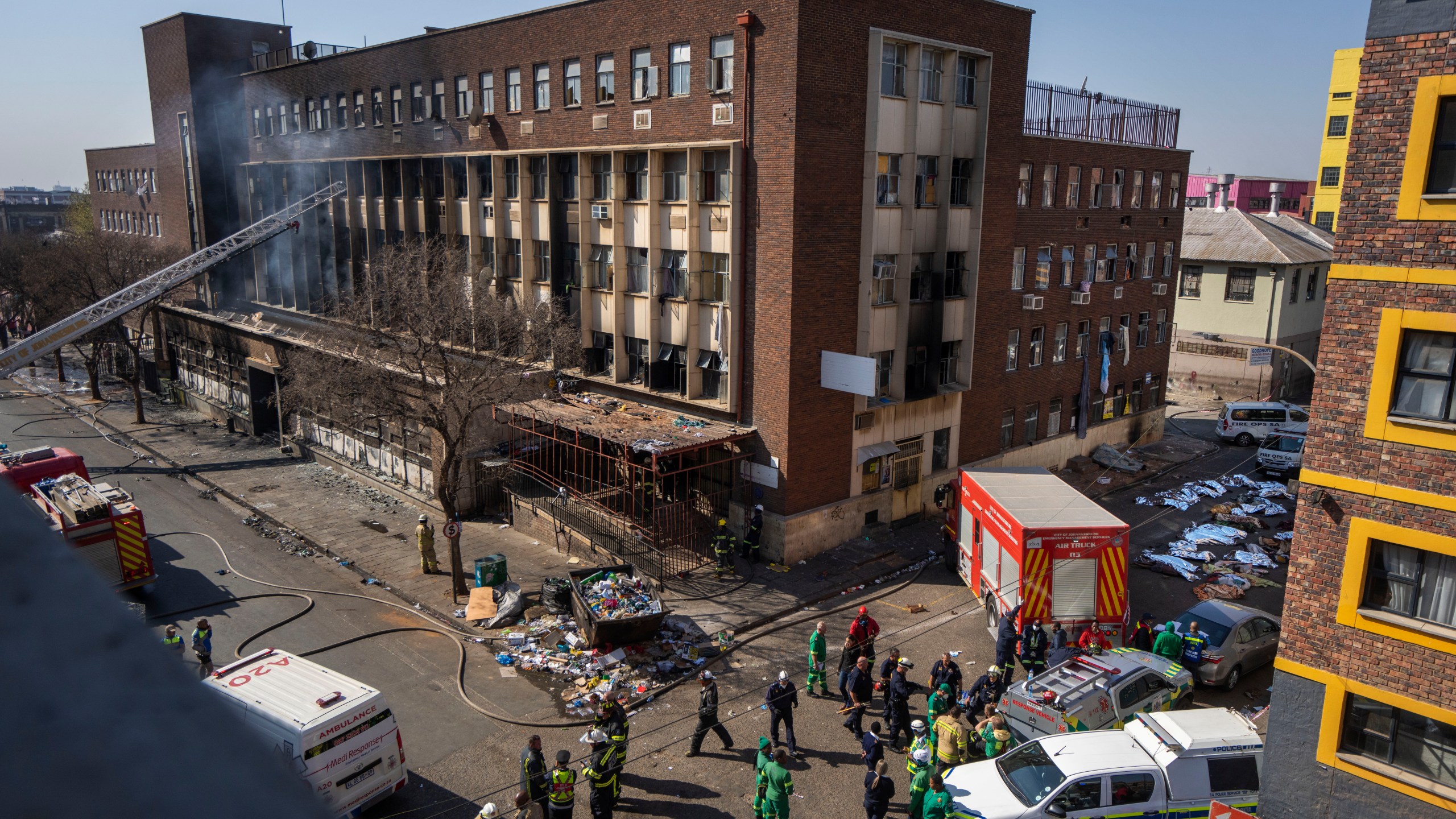 FILE - Medics and emergency works at the scene of a deadly blaze in Johannesburg Thursday, Aug. 31, 2023. A report into a building fire that killed 76 people in South Africa last year has concluded that city authorities should be held responsible because they were aware of serious safety issues at the rundown apartment block at least four years before the blaze. The nighttime fire at the five-story building in downtown Johannesburg on Aug. 31 was one of South Africa's worst disasters. At least 12 children were among the dead and another 86 people were injured. (AP Photo/Jerome Delay, File)