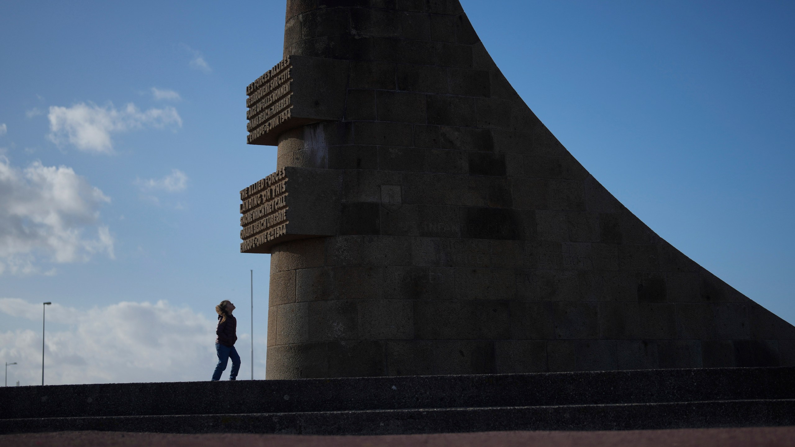 A girl watches the monument called Signal, dedicated to the American soldiers who landed on Omaha Beach on D-Day, on Omaha Beach at sunset, in Saint-Laurent-sur-Mer, Normandy, Tuesday, April 9, 2024. On D-Day, Charles Shay was a 19-year-old Native American army medic who was ready to give his life — and actually saved many. Now 99, he's spreading a message of peace with tireless dedication as he's about to take part in the 80th celebrations of the landings in Normandy that led to the liberation of France and Europe from Nazi Germany occupation. (AP Photo/Thibault Camus)