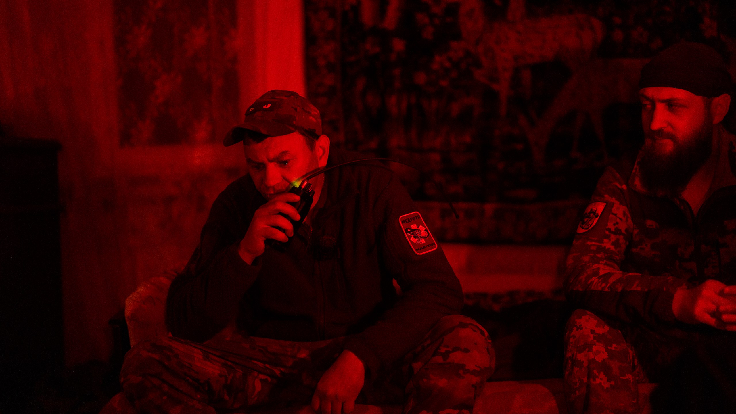 Paramedic evacuation crew driver codename Kum, left, talks on a walkie talkie next to comrade codename Livsi as they wait for injured soldiers in an medical point in the area of Avdiivka close to Donetsk, Ukraine, Saturday, May 4, 2024. (AP Photo/Francisco Seco)