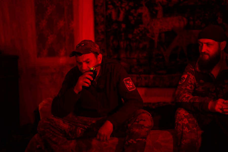 Paramedic evacuation crew driver codename Kum, left, talks on a walkie talkie next to comrade codename Livsi as they wait for injured soldiers in an medical point in the area of Avdiivka close to Donetsk, Ukraine, Saturday, May 4, 2024. (AP Photo/Francisco Seco)