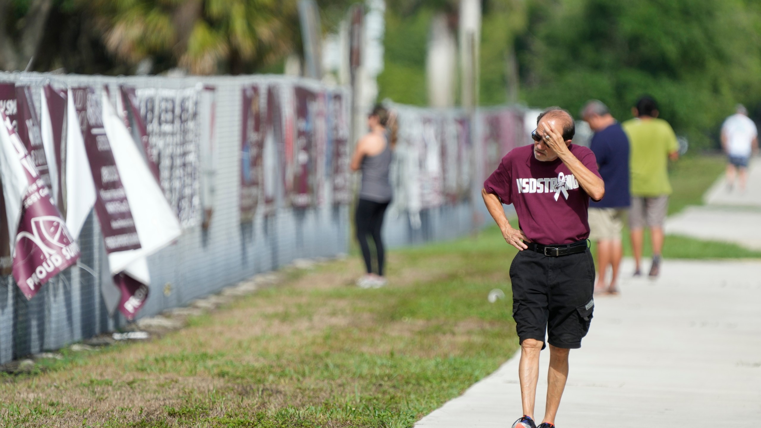 A passerby walks past after watching crews start the demolition of the Marjory Stoneman Douglas High School building, Friday, June 14, 2024, where 17 people died in a 2018 mass shooting in Parkland, Fla. Officials plan to complete the weekslong project before the school's 3,300 students return in August from summer vacation. (AP Photo/Wilfredo Lee)