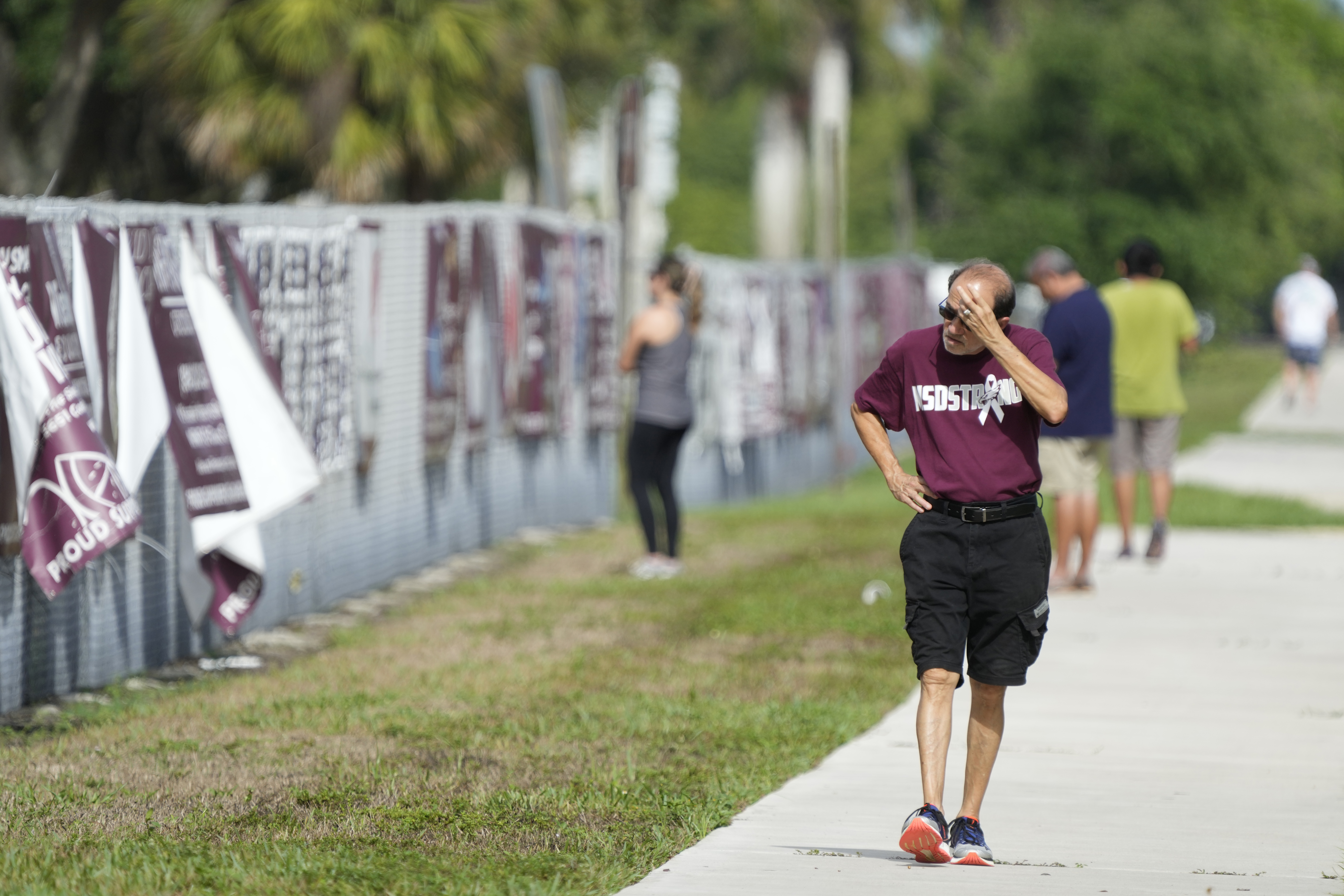 A passerby walks past after watching crews start the demolition of the Marjory Stoneman Douglas High School building, Friday, June 14, 2024, where 17 people died in a 2018 mass shooting in Parkland, Fla. Officials plan to complete the weekslong project before the school's 3,300 students return in August from summer vacation. (AP Photo/Wilfredo Lee)