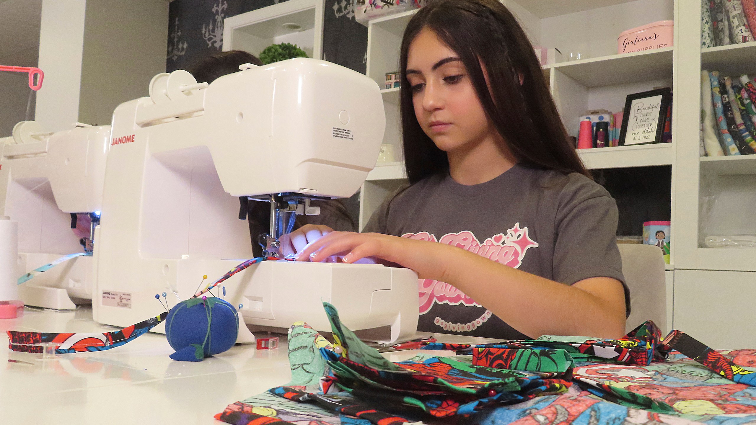 Audrina Demma sews a pediatric hospital gown in the basement of her Freehold, N.J., home on June 19, 2024. Giuliana and Audrina Demma have sewn and donated 1,800 hospital gowns to sick children in 36 states plus Africa. Giuliana was inspired by seeing her baby cousin wearing an ugly, ill-fitting gown while hospitalized with brain cancer in 2017. (AP Photo/Wayne Parry)