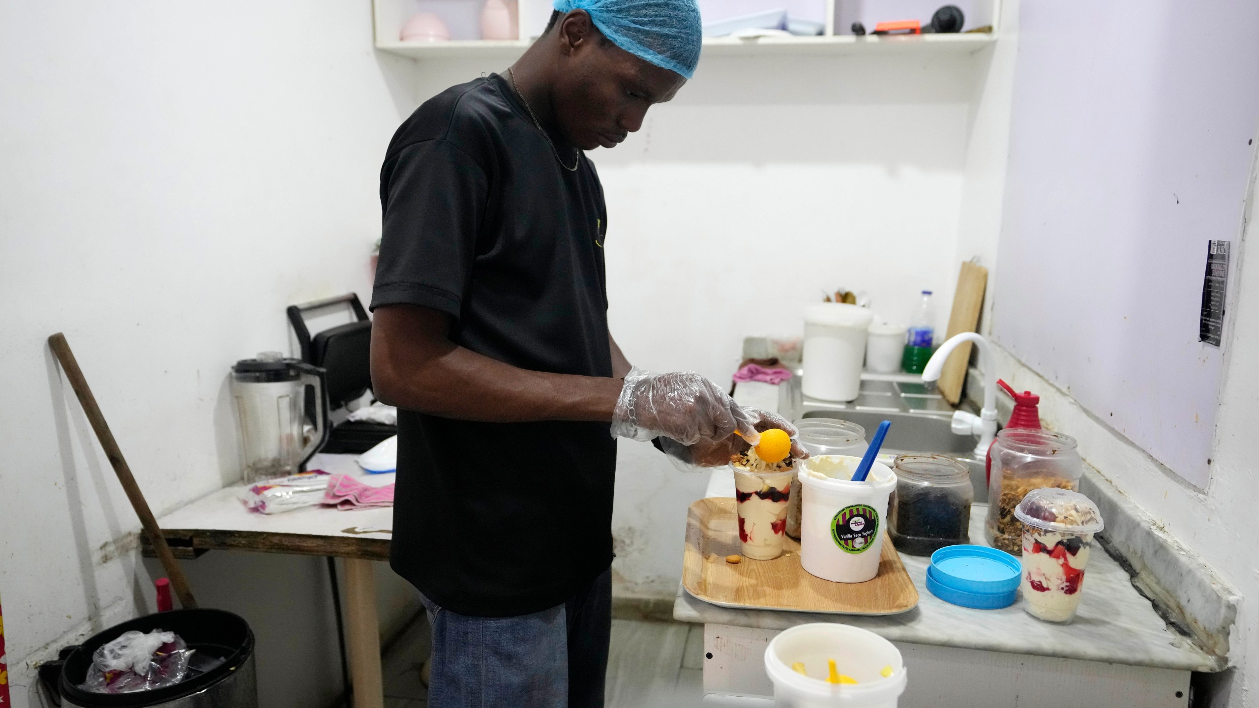 A worker with Nature's Treat Cafe prepares a parfait for a customer in Ibadan, Nigeria, Monday, May 27, 2024. Households and businesses often use polluting gasoline and diesel-run backup private generators. But as fuel prices rise, businesses like Nature's Treat Cafe face unsustainable generator costs, prompting a push for affordable solar solutions. (AP Photo/Sunday Alamba)