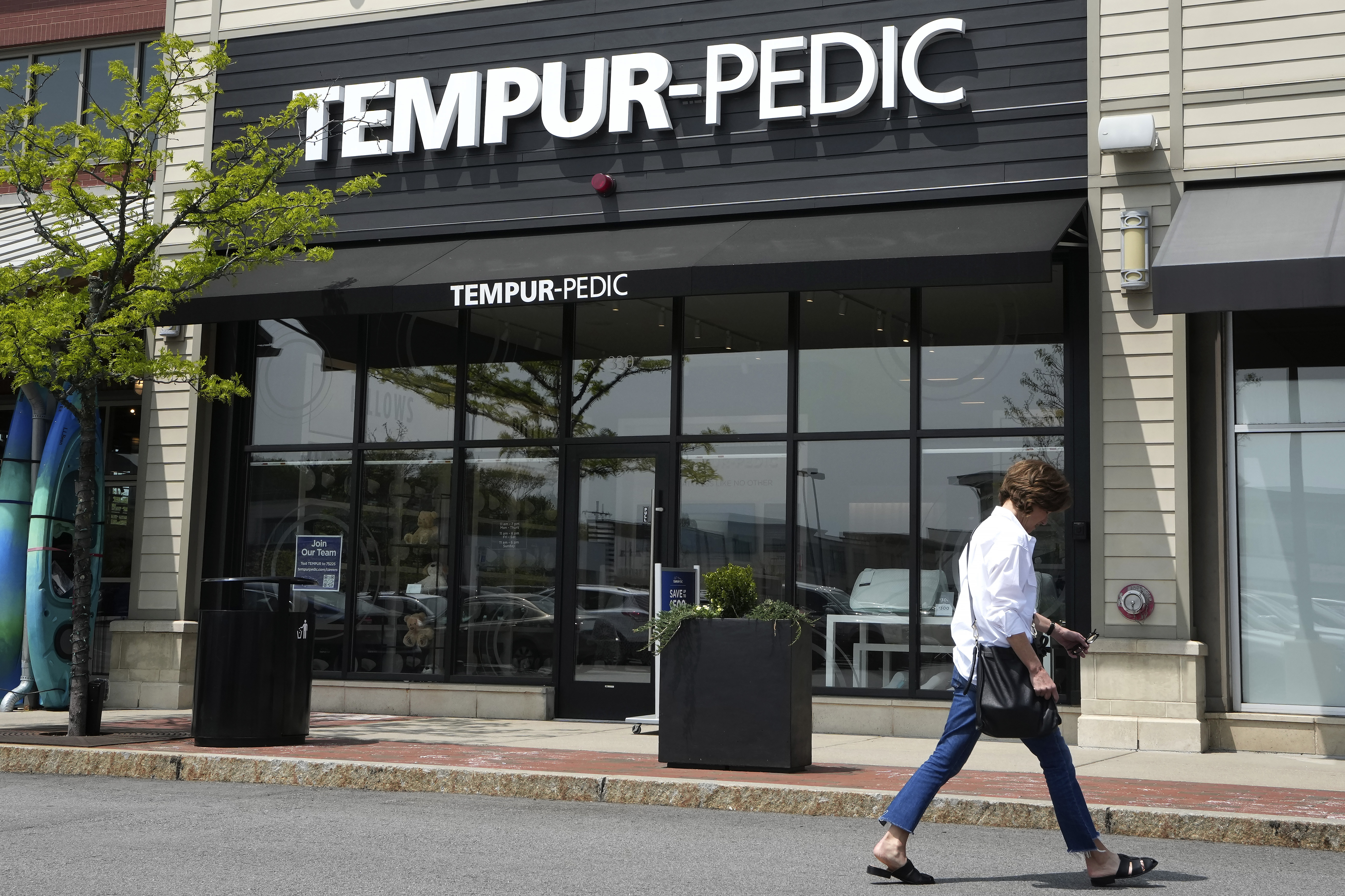FILE - A passer-by walks near the front of a Tempur-Pedic mattress store location, May 9, 2023, in Dedham, Mass. The Federal Trade Commission has unanimously voted to bring a lawsuit against mattress maker Tempur Sealy to block its $4 billion acquisition of Mattress Firm, saying the deal would allow the world’s largest mattress supplier to suppress competition that would result in higher prices for shoppers. (AP Photo/Steven Senne, File)