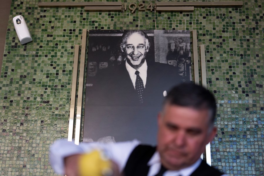 Salad Master Efrain Montoya prepares a Caesar salad in front of an image of the inventor of the salad, Caesar Cardini, at Ceasar's restaurant Thursday, June 27, 2024, in Tijuana, Mexico. Caesar salad has something to celebrate: It's turning 100. Italian immigrant Caesar Cardini is said to have invented the dish on July 4, 1924, at his restaurant, Caesar's Place, in Tijuana, Mexico. (AP Photo/Gregory Bull)