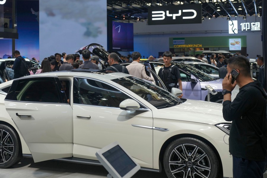 FILE - Visitors look at cars at the BYD booth during the China Auto Show in Beijing, China, Friday, April 26, 2024. The European Union threatened on Wednesday, june 12, 2024, to hike tariffs on Chinese electric vehicles, escalating a trade dispute over Beijing's subsidies for the exports that Brussels worries is hurting domestic automakers. (AP Photo/Tatan Syuflana, File)