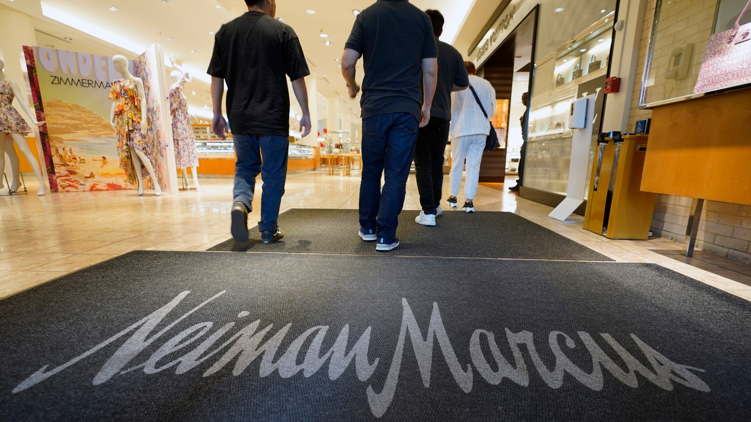 FILE - Shoppers walk into the Neiman Marcus retail department store at NorthPark shopping center in Dallas, March 30, 2023. The parent company of Saks Fifth Avenue has signed a deal to buy upscale rival Neiman Marcus for $2.65 billion. The buyout was announced Thursday, July 4, 2024, after months of rumors that the department store chains had been negotiating a deal. (AP Photo/LM Otero, File)