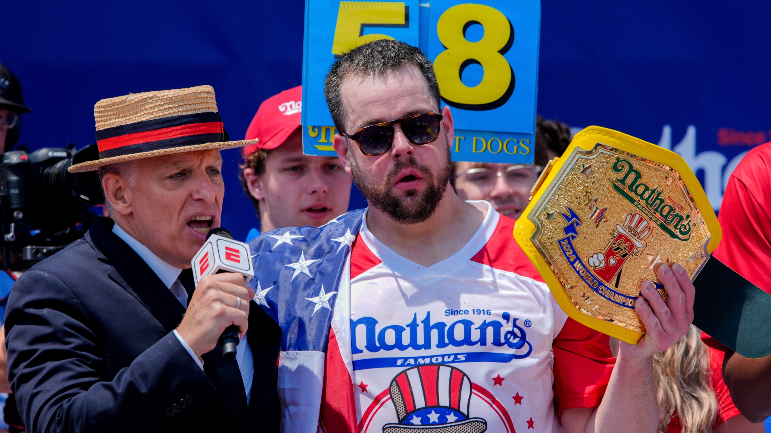 Patrick Bertoletti, right, reacts after winning the men's division in Nathan's Famous Fourth of July hot dog eating contest, Thursday, July 4, 2024, at Coney Island in the Brooklyn borough of New York. Bertoletti ate 58 hot dogs. (AP Photo/Julia Nikhinson)