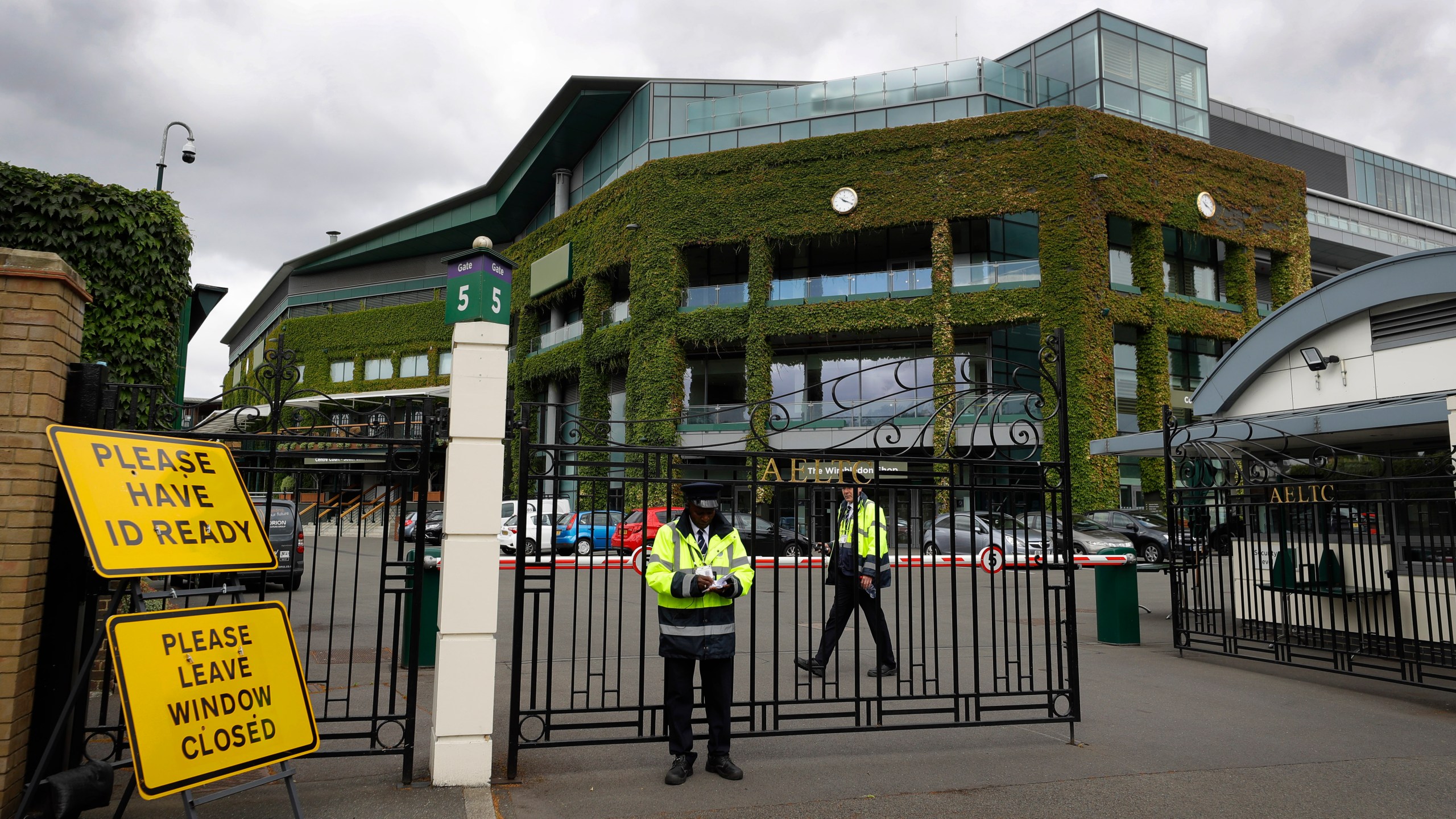 FILE - Security guards are shown at the gate in front of Centre Court at the All England Lawn Tennis Club, after the 2020 tennis championships were canceled due to the coronavirus, in Wimbledon, London, Monday, June 29, 2020. This year's Wimbledon tournament begins on Monday, July 1. (AP Photo/Kirsty Wigglesworth, File)