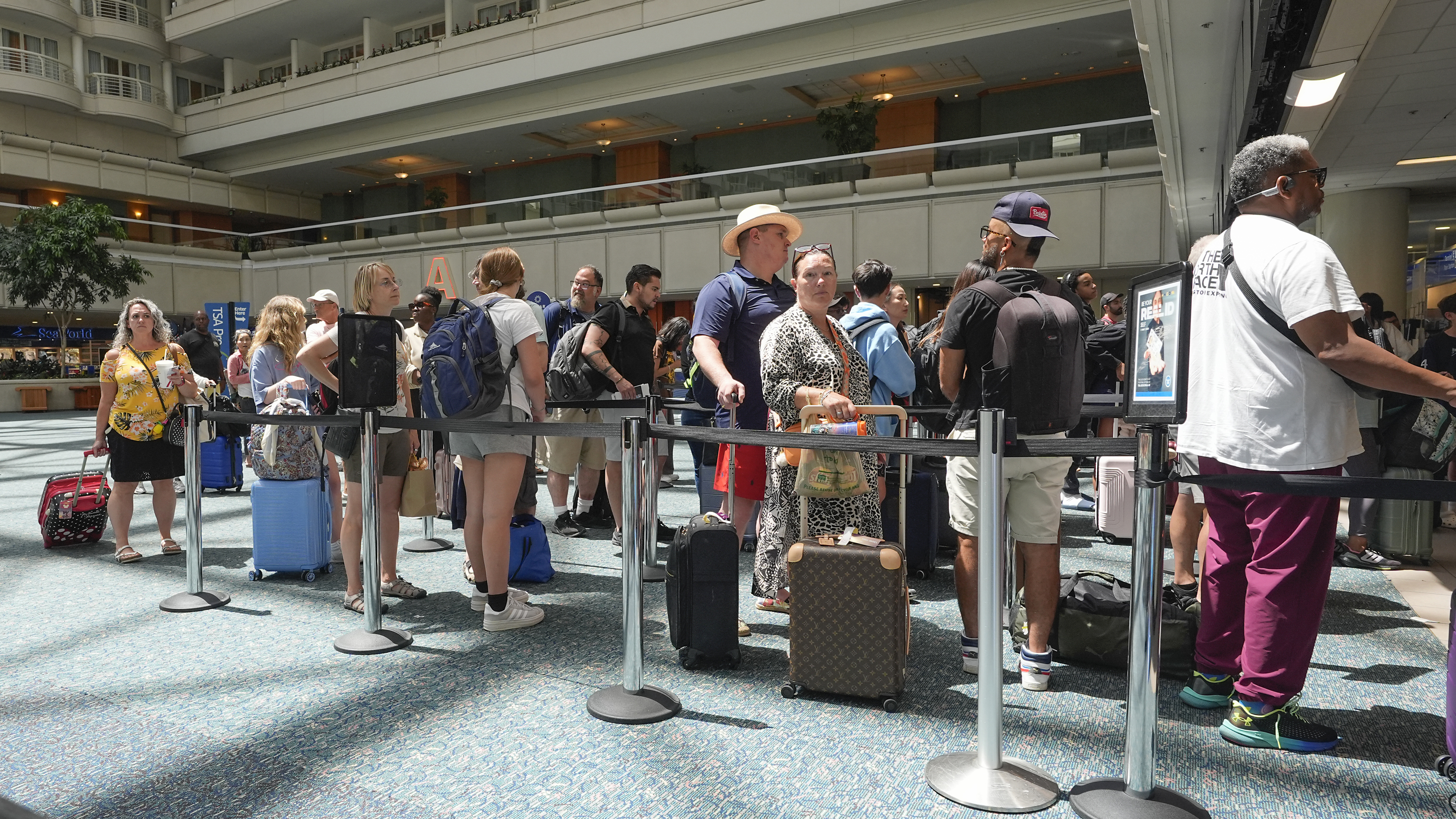 Passengers wait in line to go through TSA security screening at Orlando International Airport Wednesday, July 3, 2024, in Orlando, Fla. (AP Photo/John Raoux)