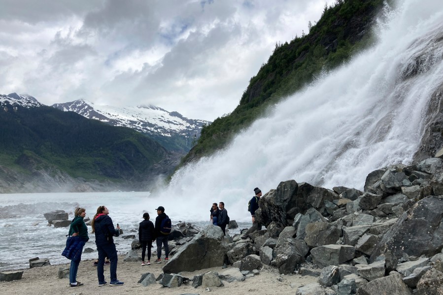 FILE - People gather near the base of Nugget Falls, a popular destination for selfies on June 13, 2023, at the Mendenhall Glacier Recreation Area, in Juneau, Alaska. Voters in Alaska's capital city could decide in October whether to ban large cruise ships on Saturdays starting next year. Supporters of the proposal say it would give residents a reprieve from the crush of tourists drawn to attractions like Juneau's fast-retreating Mendenhall Glacier, but opponents say it would hurt local businesses and invite lawsuits. (AP Photo/Becky Bohrer, File)