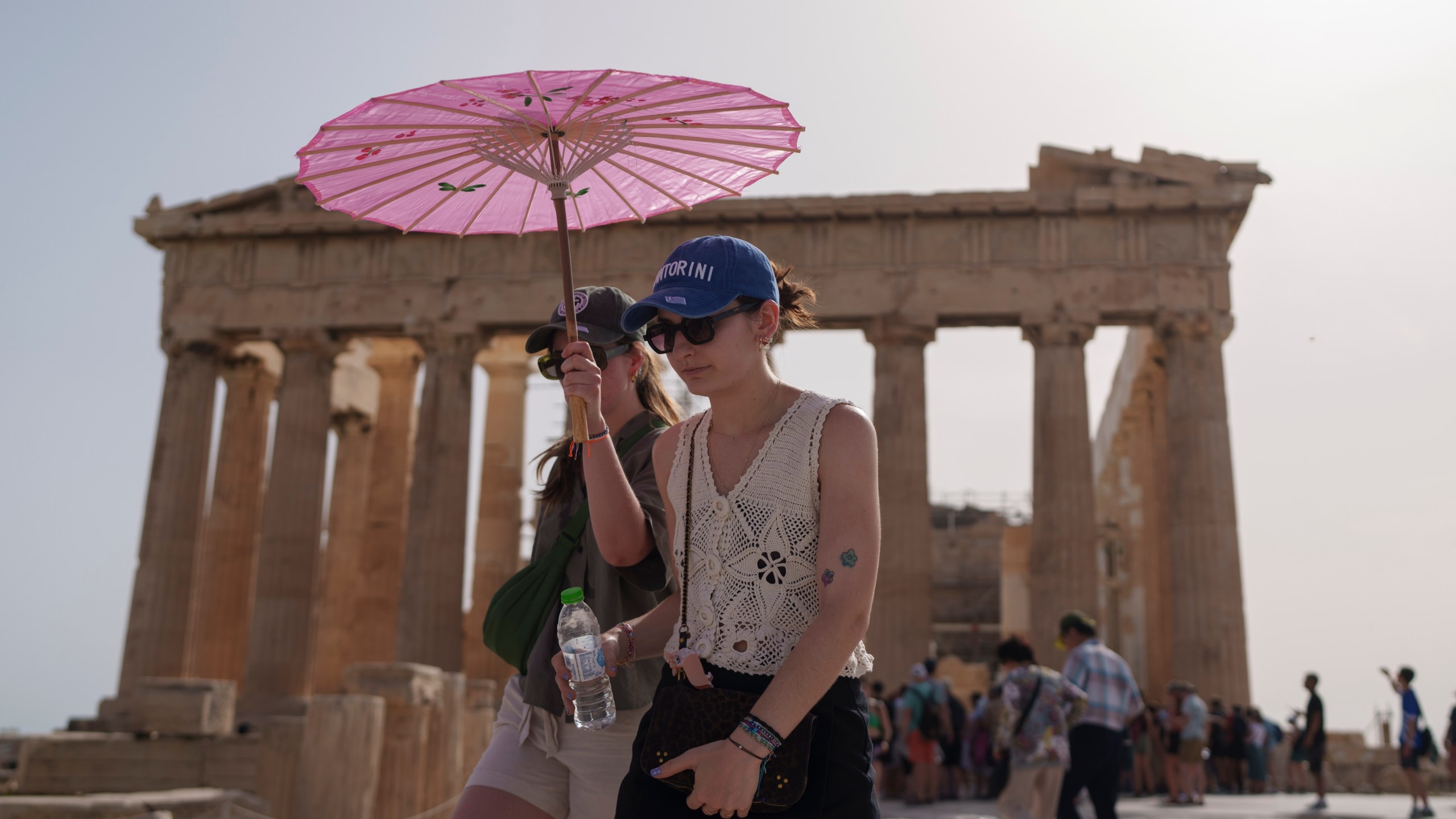 FILE - Tourists with an umbrella walk in front of the Parthenon at the ancient Acropolis in central Athens, June 12, 2024. June 2024 was the hottest June on record, according to Europe's Copernicus climate service on Monday, July 8. (AP Photo/Petros Giannakouris, File)