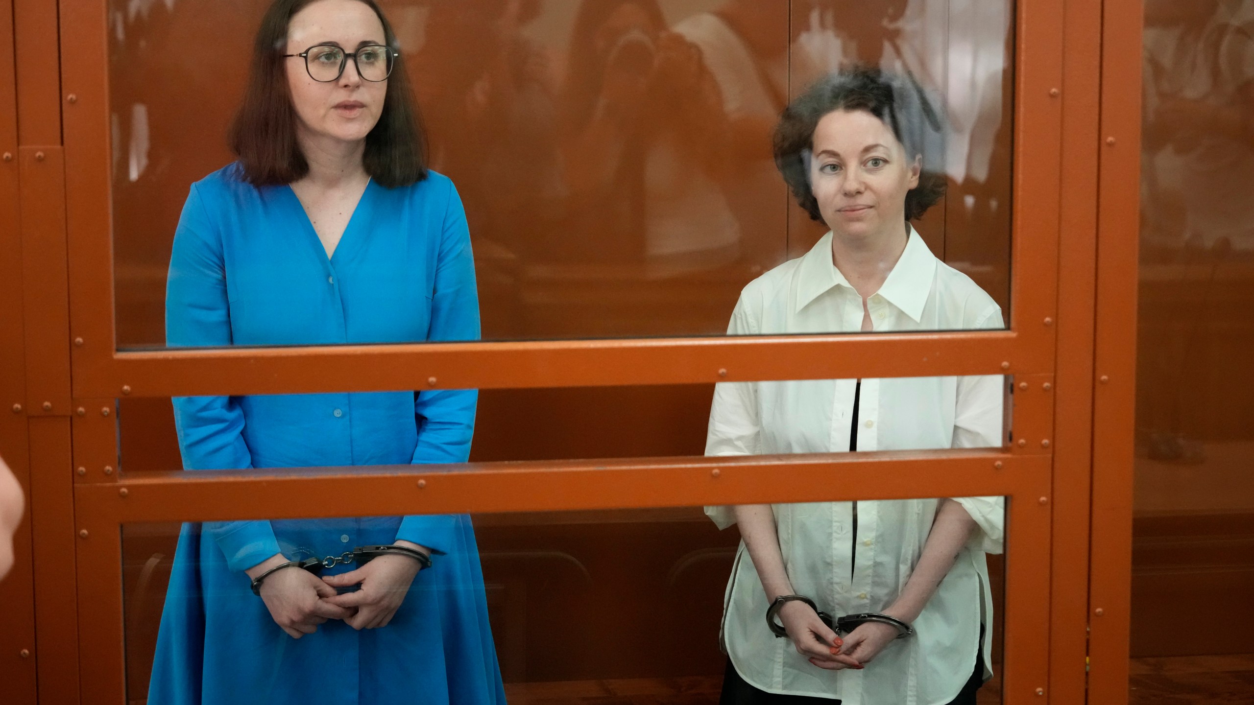 Theater director Zhenya Berkovich, right, and playwright Svetlana Petriychuk are seen in a glass cage prior to a hearing in a court in Moscow, Russia, Monday, July 8, 2024. Berkovich, a prominent independent theater director, and Petriychuk, a playwright have been behind bars since early May. Authorities claim a play they staged, "Finist, the Brave Falcon," justifies terrorism, which is a criminal offence in Russia punishable by up to seven years in prison. (AP Photo/Alexander Zemlianichenko)