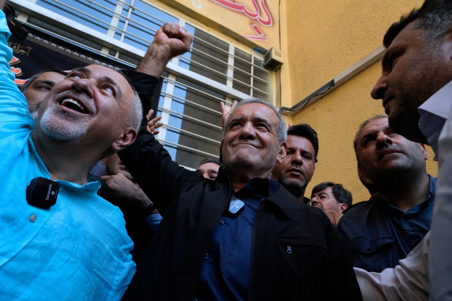 Reformist candidate for the Iran's presidential election Masoud Pezeshkian clenches his fist after casting his vote as he is accompanied by former Foreign Minister Mohammad Javad Zarif, left, at a polling station in Shahr-e-Qods near Tehran, Iran, Friday, July 5, 2024. Iranians are voting in a runoff election to replace the late President Ebrahim Raisi, who was killed in a May helicopter crash in the country’s northwest along with the foreign minister and several other officials. (AP Photo/Vahid Salemi)