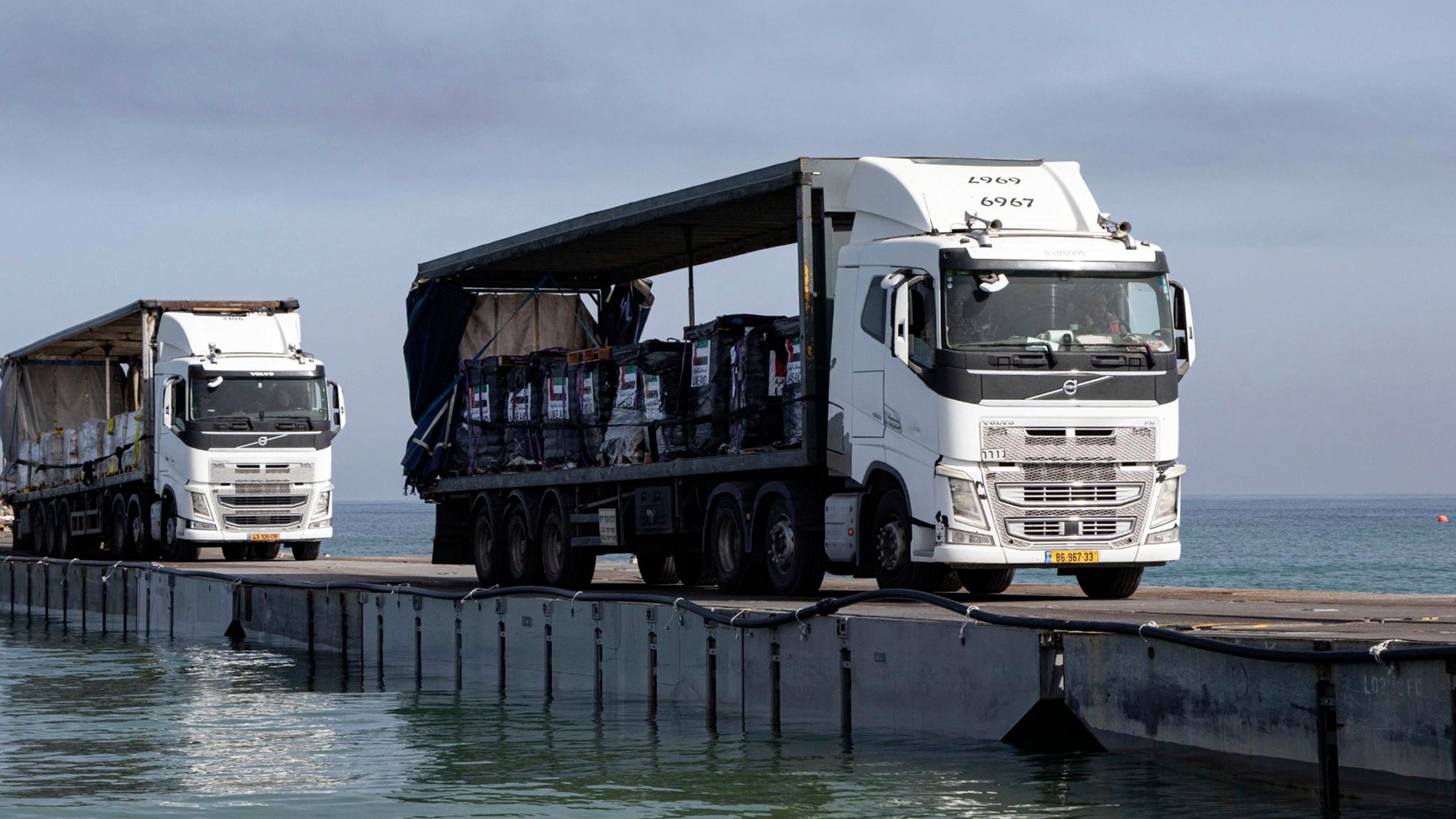 FILE - This image provided by the U.S. Army shows trucks loaded with humanitarian aid from the United Arab Emirates and the United States Agency for International Development cross the Trident Pier before arriving on the beach on the Gaza Strip, May 17, 2024. The U.S. military-built pier to carry humanitarian aid to Gaza is being dismantled and brought home, ending a mission that has been fraught with weather and security problems. (Staff Sgt. Malcolm Cohens-Ashley/U.S. Army via AP, File)