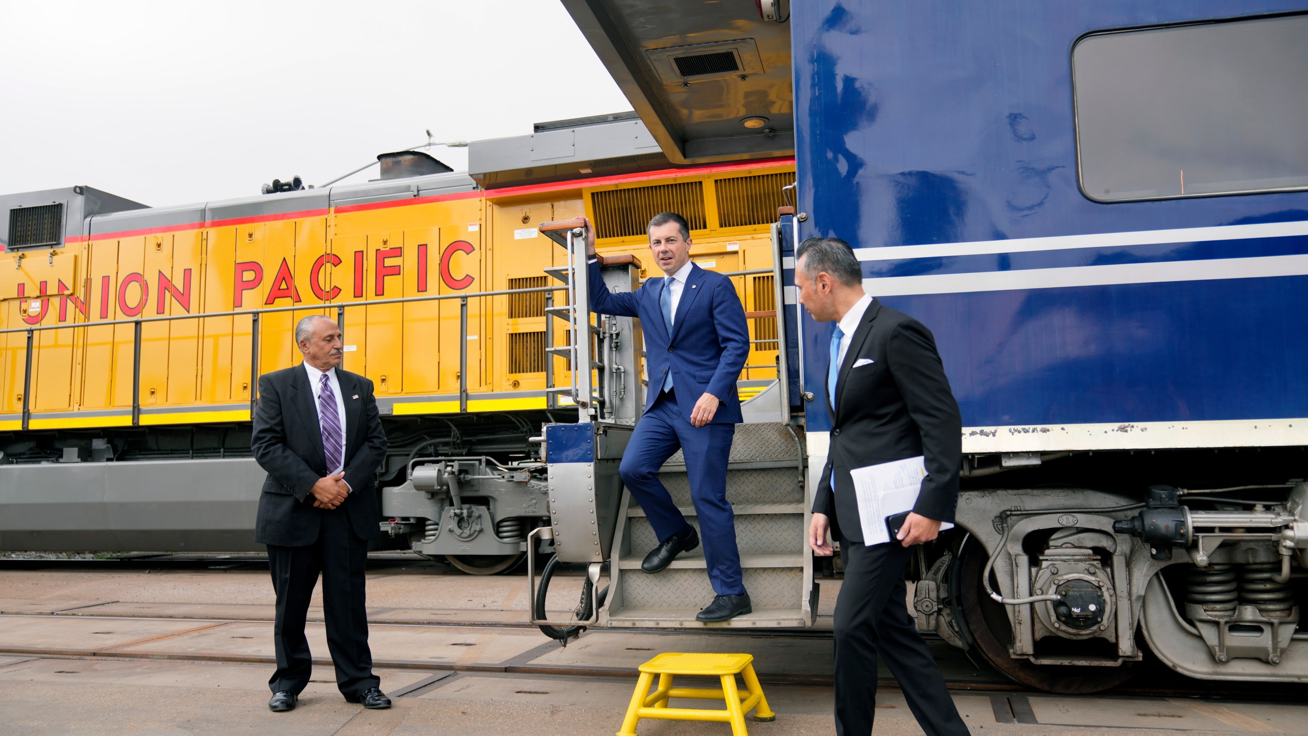 US Secretary of Transportation Pete Buttigieg, middle, steps off a railcar pulled by a PHL Joule Zero-Emission Engine to attend the groundbreaking for "America's Green Gateway," at the Pier B On-Dock Rail Support Facility in Long Beach, Calif., on Thursday, July 18, 2024. Secretary Buttigieg visited the Port of Los Angeles for the groundbreaking ceremony of a $1.5 billion rail project dubbed "America's Green Gateway" that will greatly expand service to get goods from ships across the US by train versus diesel-powered trucks that can be more polluting. (AP Photo/Damian Dovarganes)