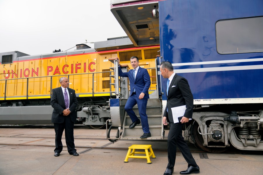 US Secretary of Transportation Pete Buttigieg, middle, steps off a railcar pulled by a PHL Joule Zero-Emission Engine to attend the groundbreaking for "America's Green Gateway," at the Pier B On-Dock Rail Support Facility in Long Beach, Calif., on Thursday, July 18, 2024. Secretary Buttigieg visited the Port of Los Angeles for the groundbreaking ceremony of a $1.5 billion rail project dubbed "America's Green Gateway" that will greatly expand service to get goods from ships across the US by train versus diesel-powered trucks that can be more polluting. (AP Photo/Damian Dovarganes)