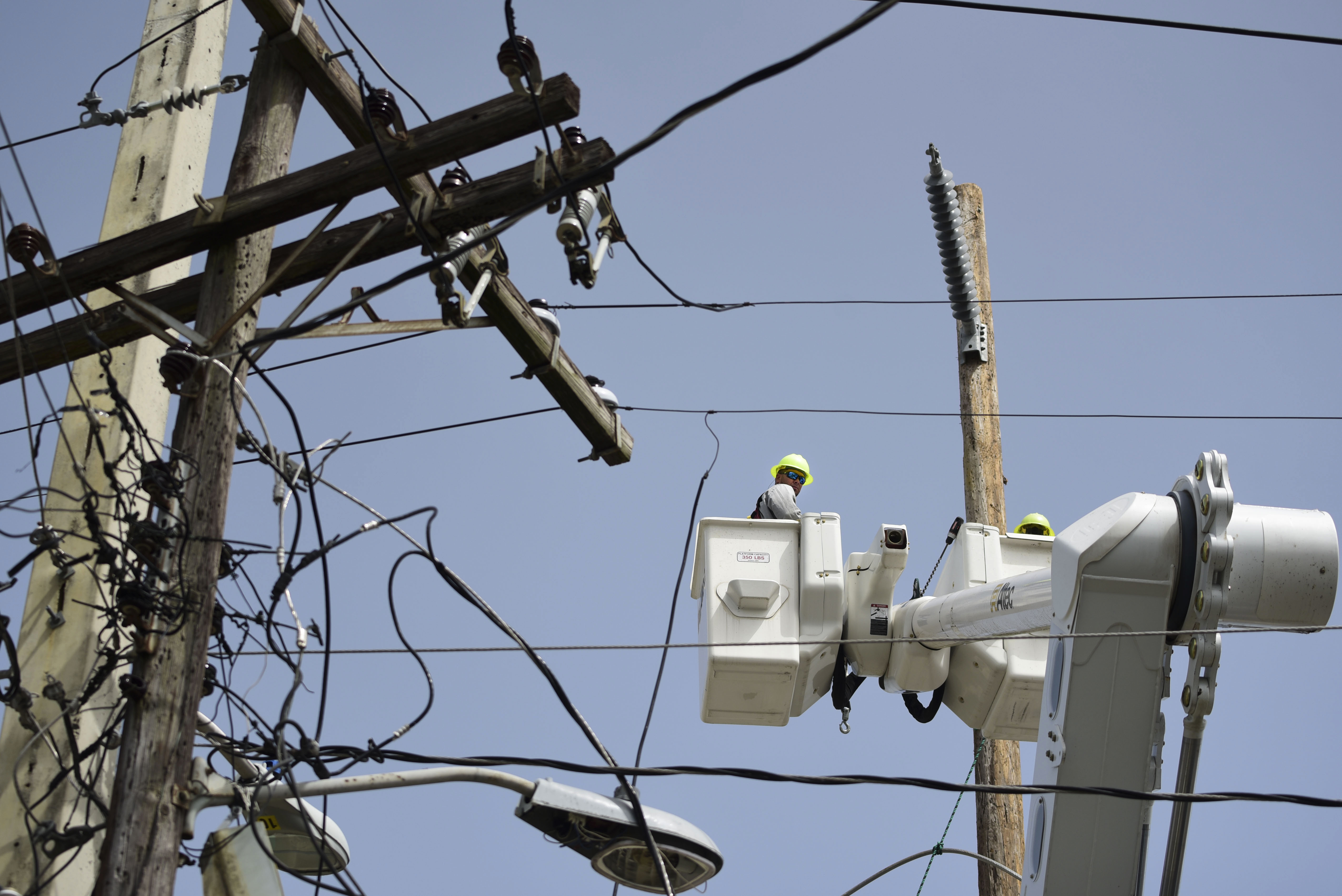 FILE - A brigade from the Electric Power Authority repairs distribution lines damaged by Hurricane Maria in the Cantera community of San Juan, Puerto Rico, Oct. 19, 2017. A federal judge overseeing a drawn-out debt-restructuring process for the power company ordered all parties to mediation on Wednesday, July 10, in the latest attempt to break an impasse that has sparked widespread anger and frustration. (AP Photo/Carlos Giusti, File)