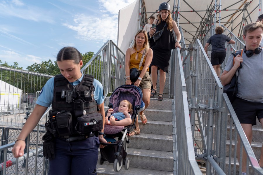 Severine Hiver, right, gets help from officer Romane Rouseel to carry her daughter, Sacha, 2, down a staircase in her stroller while navigating around a security area closed off for the 2024 Summer Olympics, Thursday, July 18, 2024, in Paris. A special kind of iron curtain came down across central Paris on Thursday, with the beginning of an Olympic anti-terrorism perimeter along the banks of the River Seine sealing off a kilometers-long (miles-long) area to Parisians and tourists who hadn't applied in advance for a pass. (AP Photo/David Goldman)