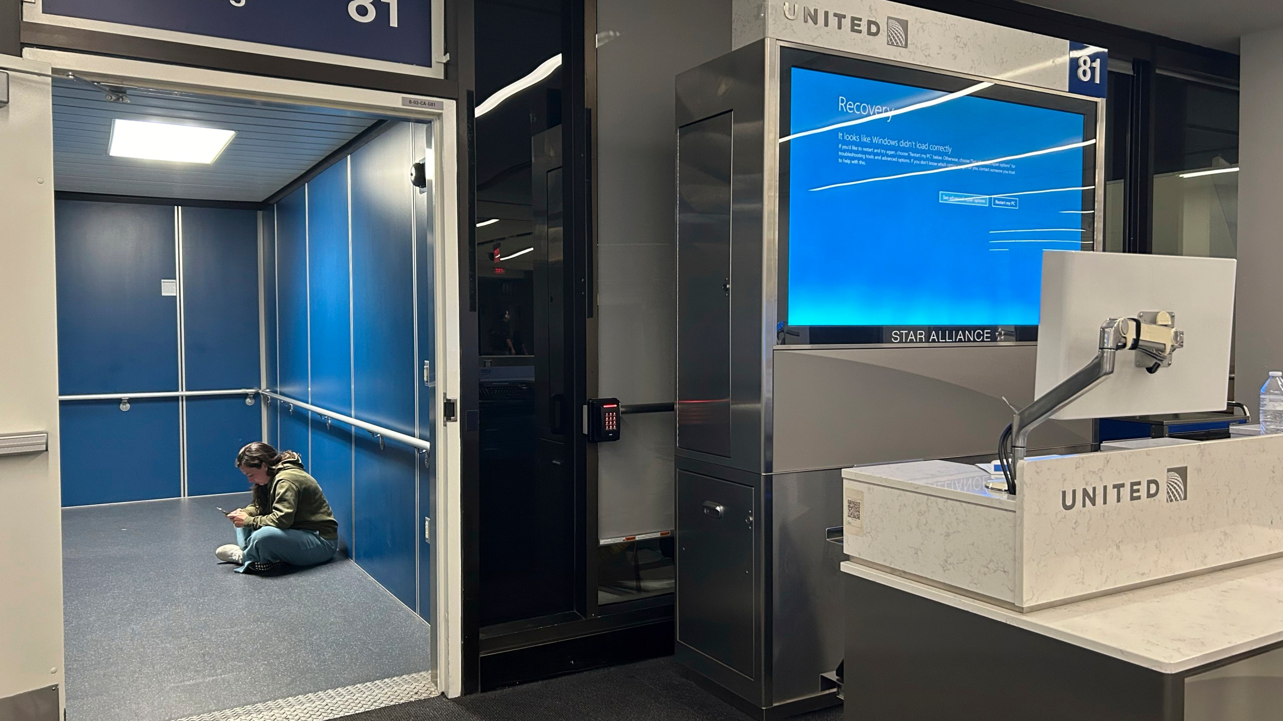 A traveler at Los Angeles International Airport sits in a jetway for a delayed United Airlines flight to Dulles International Airport due to a widespread global technology outage disrupting flights, banks, media outlets and companies around the world, Friday, July 19, 2024, in Los Angeles. (AP Photo/Stefanie Dazio)