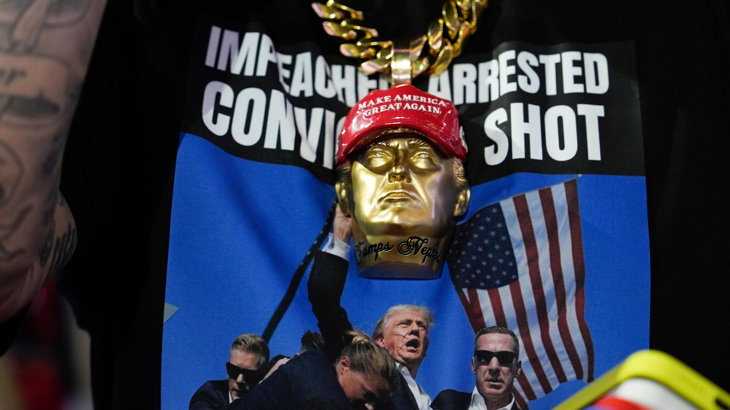 A delegate wears a tee shirt with a photo of Republican presidential candidate former President Donald Trump being surrounded by U.S. Secret Service agents at a campaign rally during the Republican National Convention Monday, July 15, 2024, in Milwaukee. (AP Photo/Julia Nikhinson)