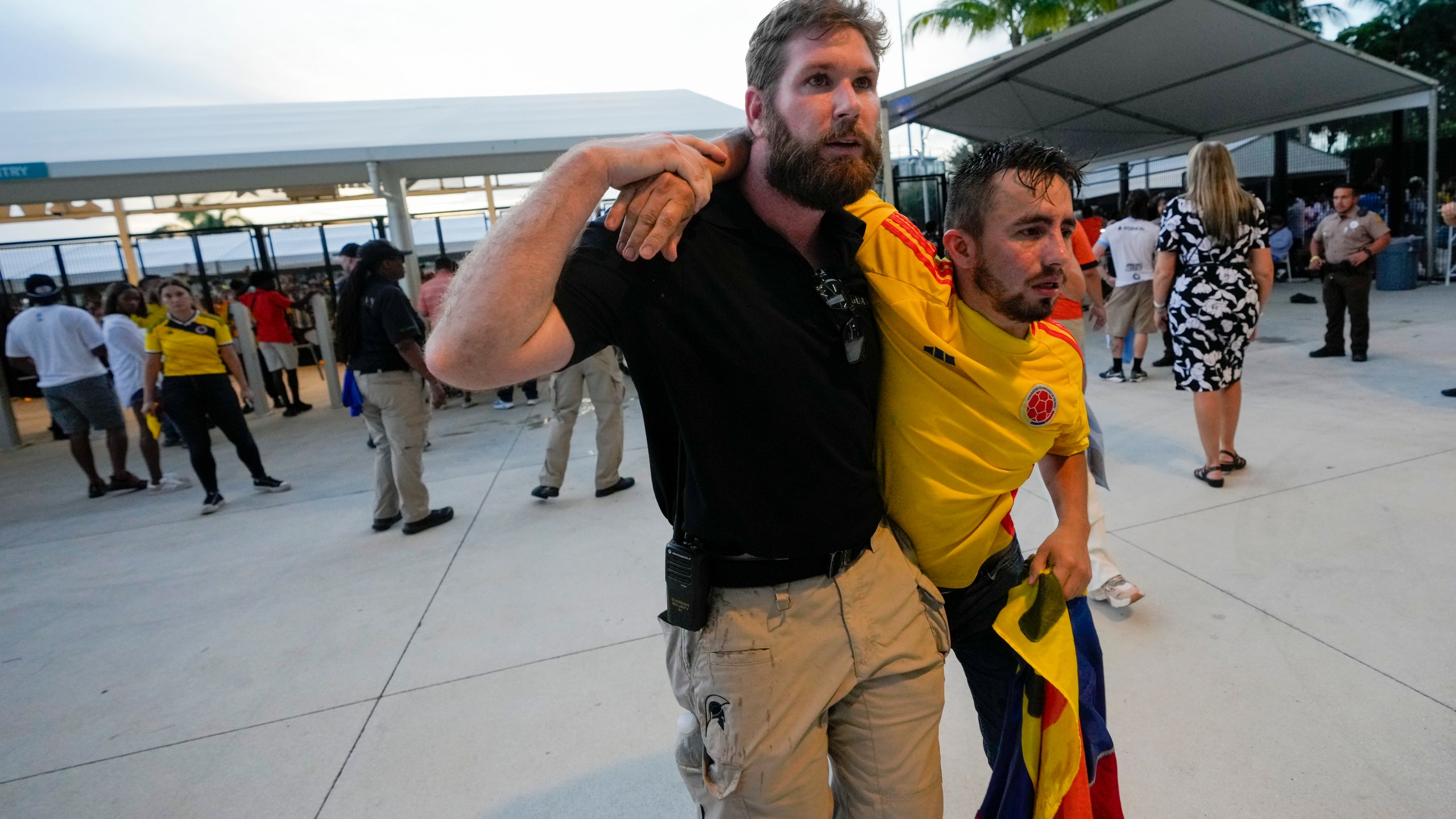 A security agent assist a fan who was waiting to enter the stadium prior to the Copa America final soccer match between Argentina and Colombia, in Miami Gardens, Fla., Sunday, July 14, 2024. (AP Photo/Lynne Sladky)