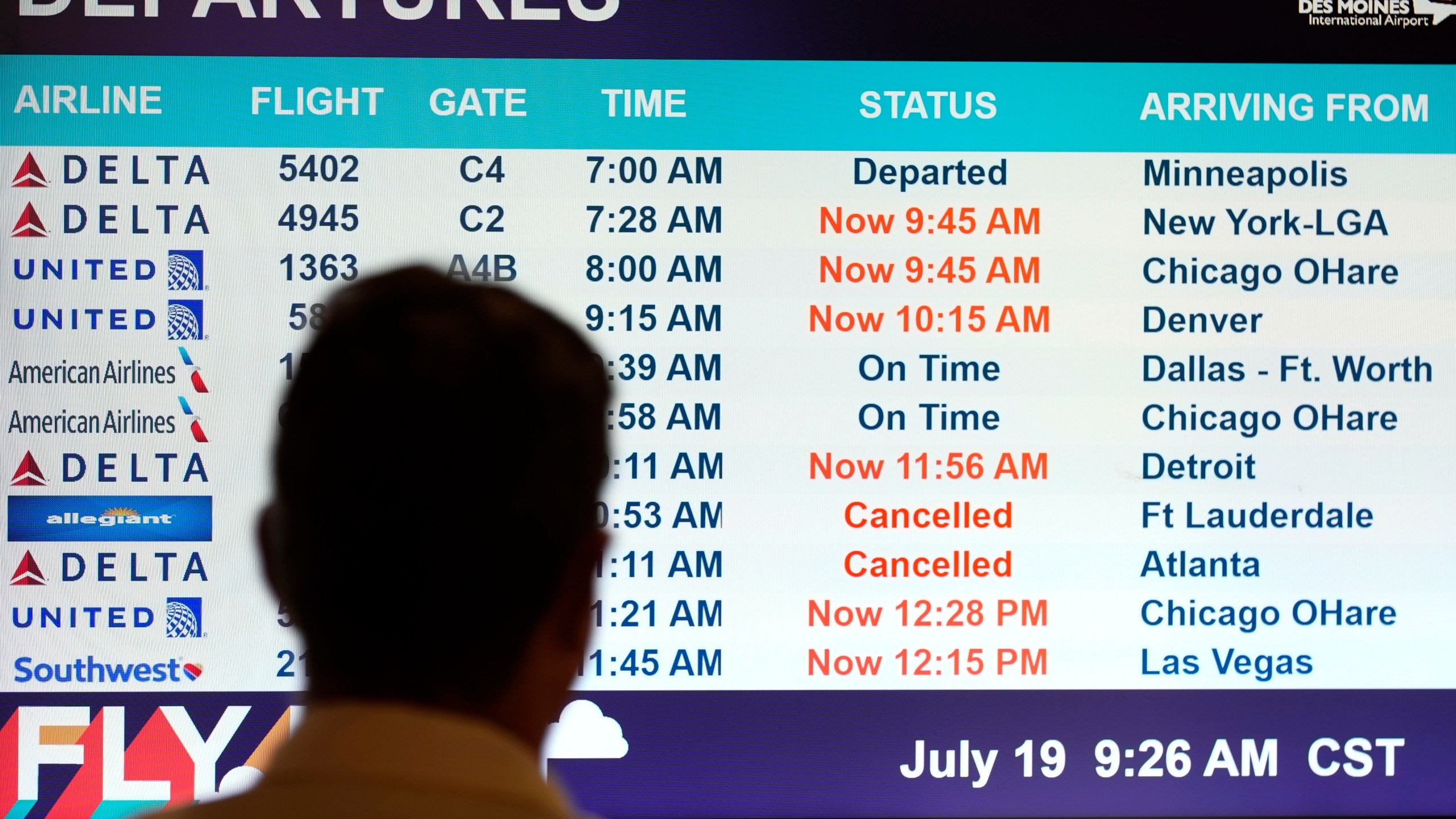 A passenger looks at a departures monitor at the Des Moines International Airport, Friday, July 19, 2024, in Des Moines, Iowa. (AP Photo/Charlie Neibergall)