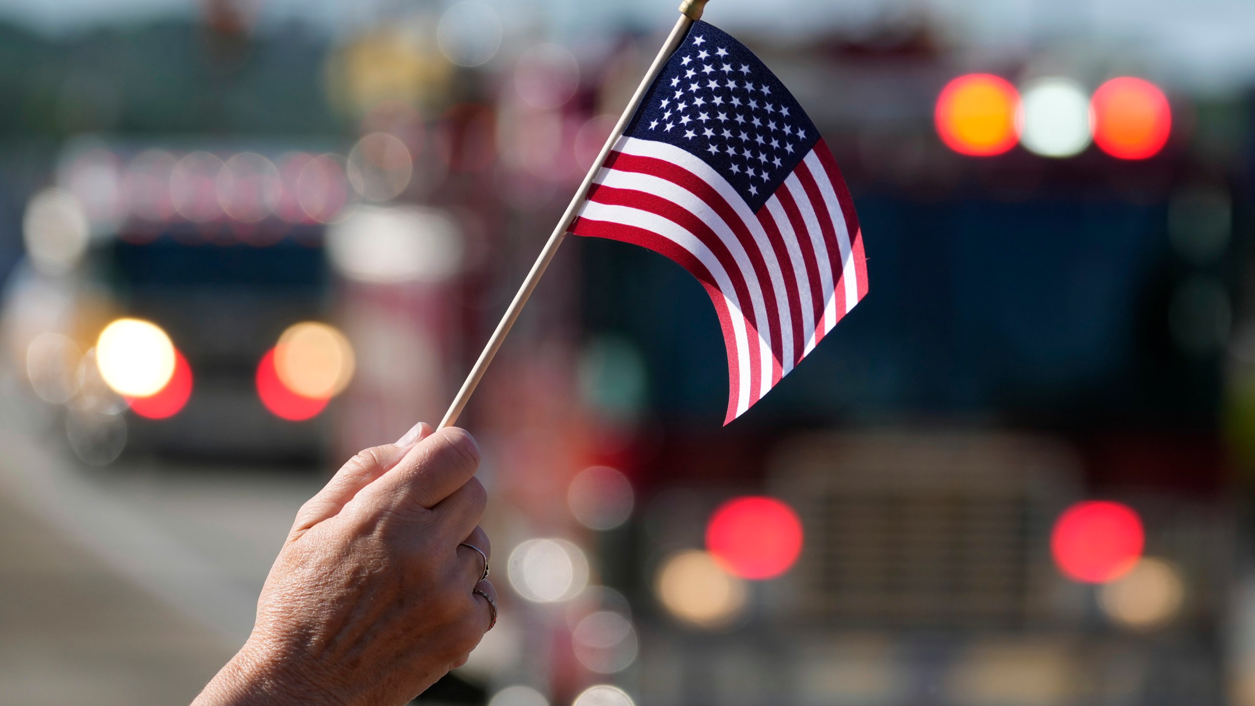 Jane Wesolosky, of Buffalo, Pa., waves a flag as the funeral procession for Corey Comperatore passes, Friday, July 19, 2024, in Sarver, Pa. Comperatore, a former fire chief, was shot and killed while attending a weekend rally for former President Donald Trump. (AP Photo/Matt Slocum)