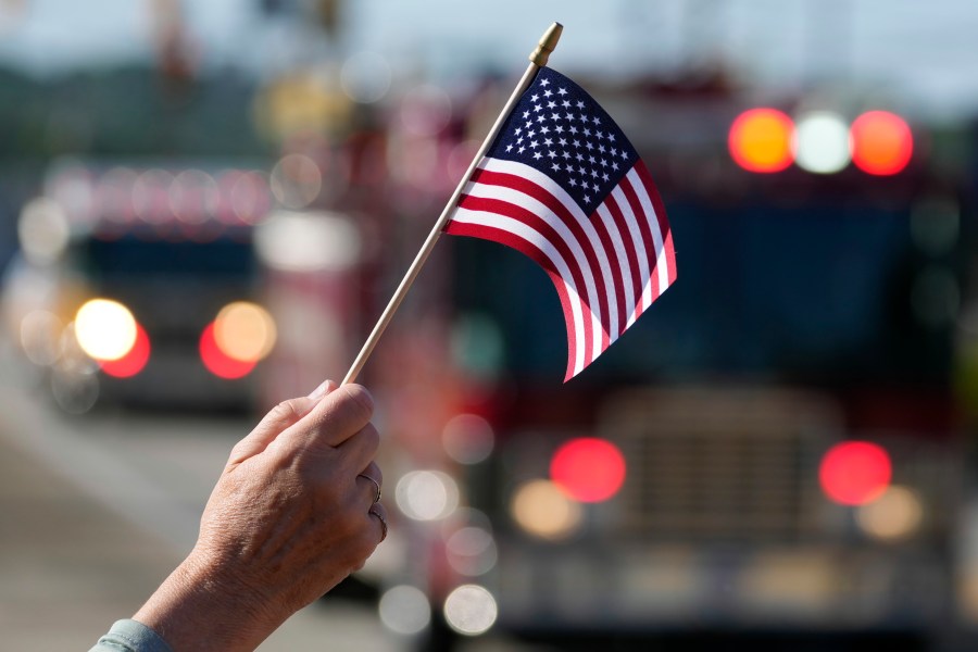 Jane Wesolosky, of Buffalo, Pa., waves a flag as the funeral procession for Corey Comperatore passes, Friday, July 19, 2024, in Sarver, Pa. Comperatore, a former fire chief, was shot and killed while attending a weekend rally for former President Donald Trump. (AP Photo/Matt Slocum)