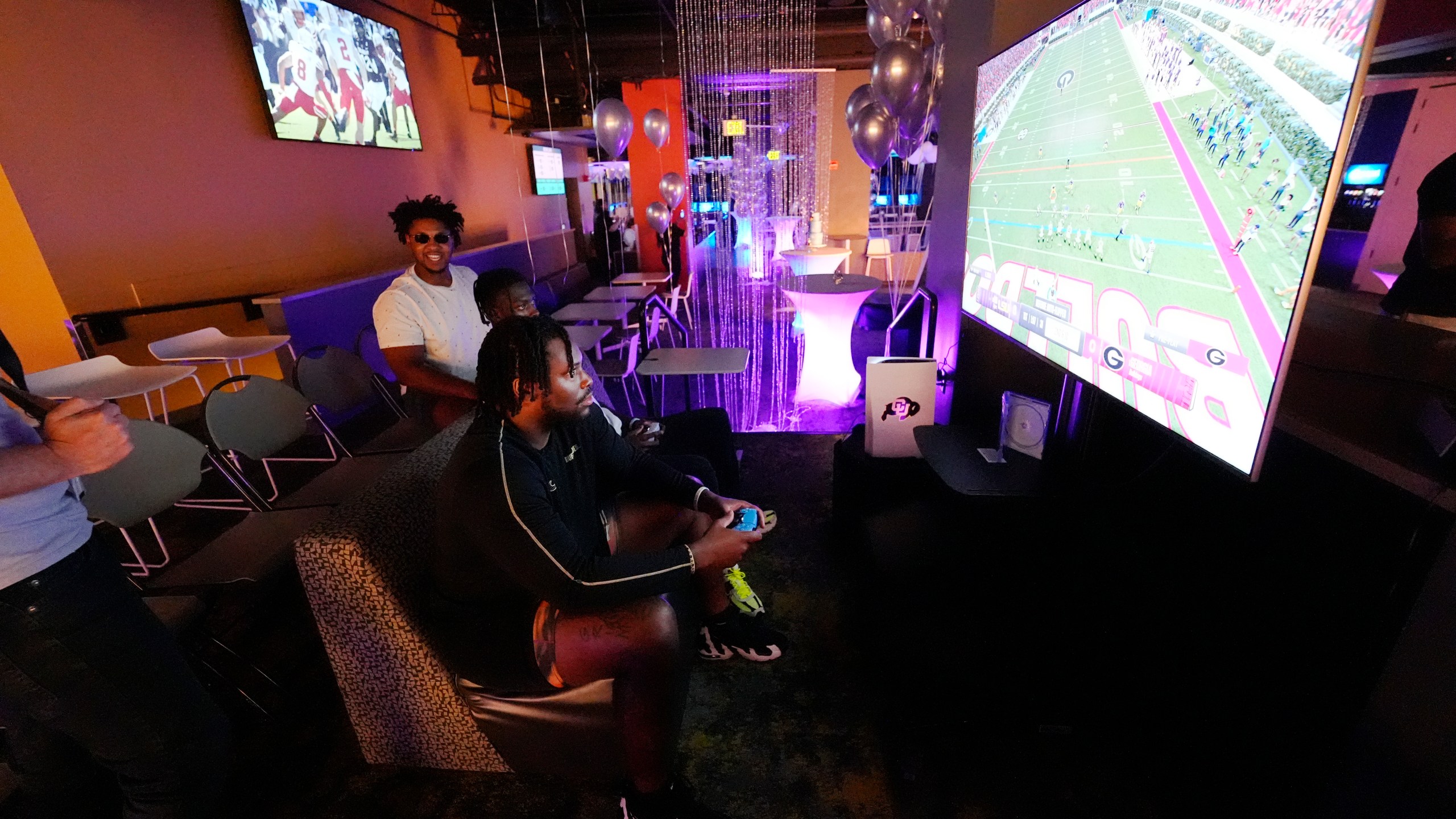 Colorado center Yakiri Walker, front, and running back Kam Mikell, center, join offensive lineman Tyler Johnson, left, in playing the EA Sports College Football 25 video game during a release party Friday, July 19, 2024, at the Memorial Union on the campus of the University of Colorado in Boulder, Colo. EA Sports College Football 25 flooded the market Friday as gamers who waited more than a decade for the franchise's next installment hurry to play. (AP Photo/David Zalubowski)