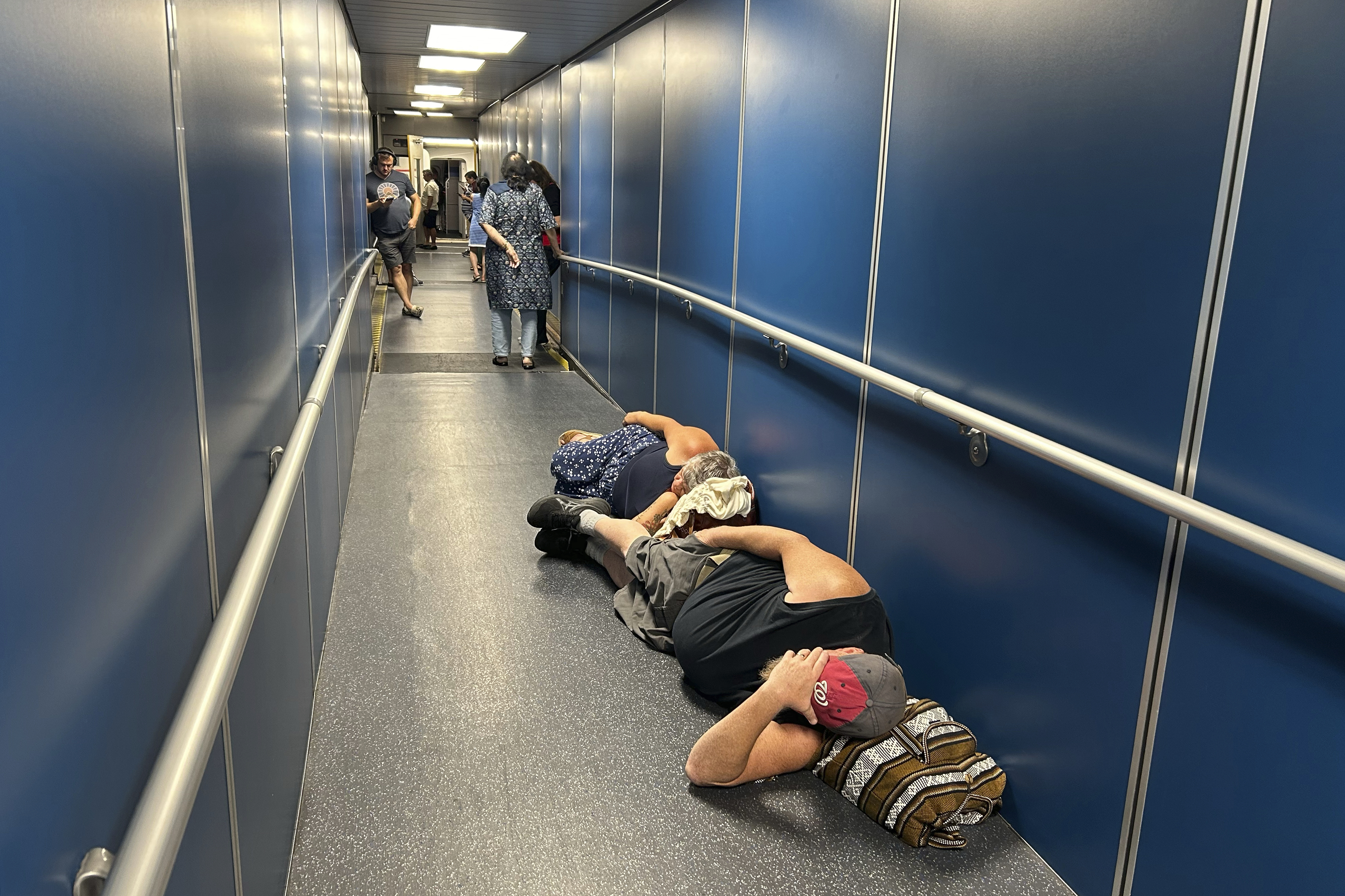 Travelers at Los Angeles International Airport sleep in a jetway for a delayed United Airlines flight to Dulles International Airport due to a widespread global outage early Friday, July 19, 2024, in Los Angeles. (AP Photo/Stefanie Dazio)