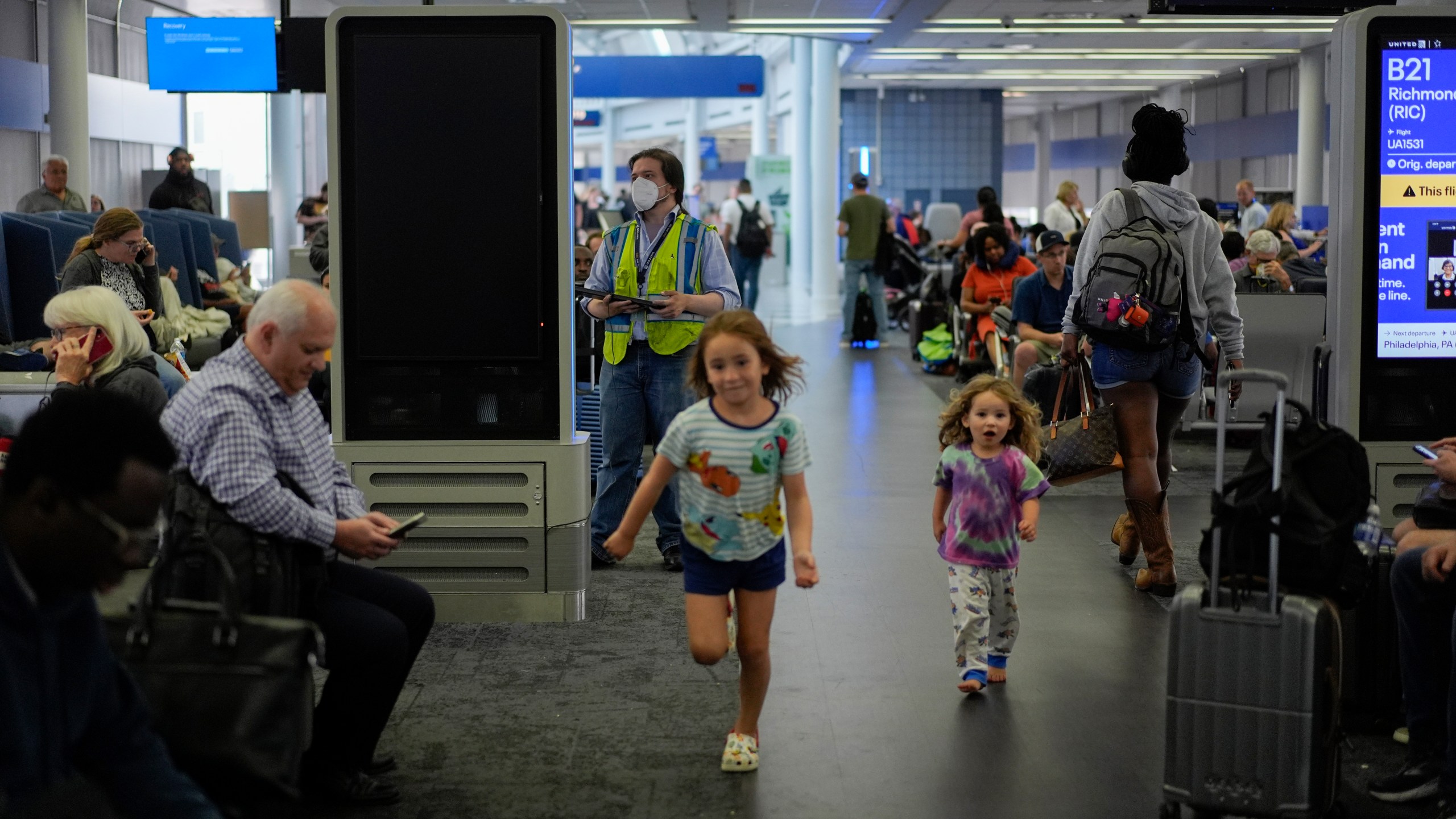 A technician removes software from an information display near United Airlines gates at the Chicago O'Hare International Airport in Chicago, Friday, July 19, 2024, after software issues delayed and canceled flights globally. (AP Photo/Carolyn Kaster)